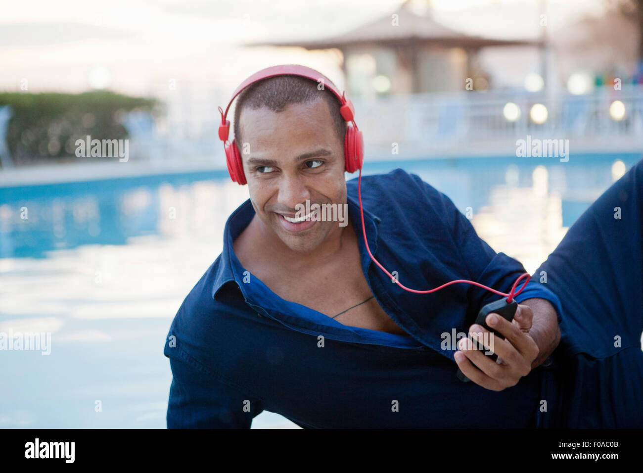 Mitte erwachsenen Mannes Smartphone Musikhören am Hotel Pool, Rio De Janeiro, Brasilien Stockfoto