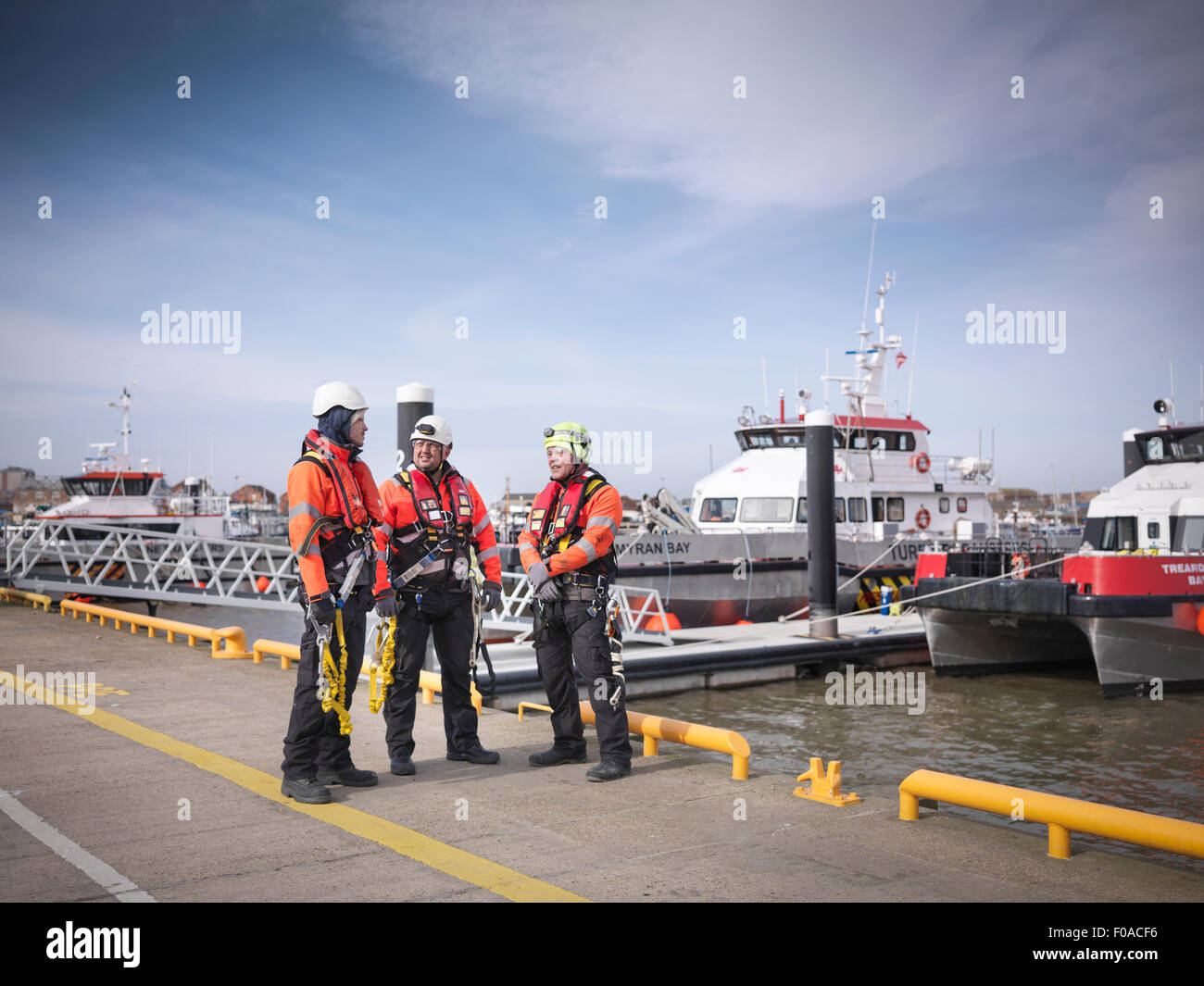 Offshore-Windpark-Ingenieure am Kai mit Booten im Hintergrund Stockfoto