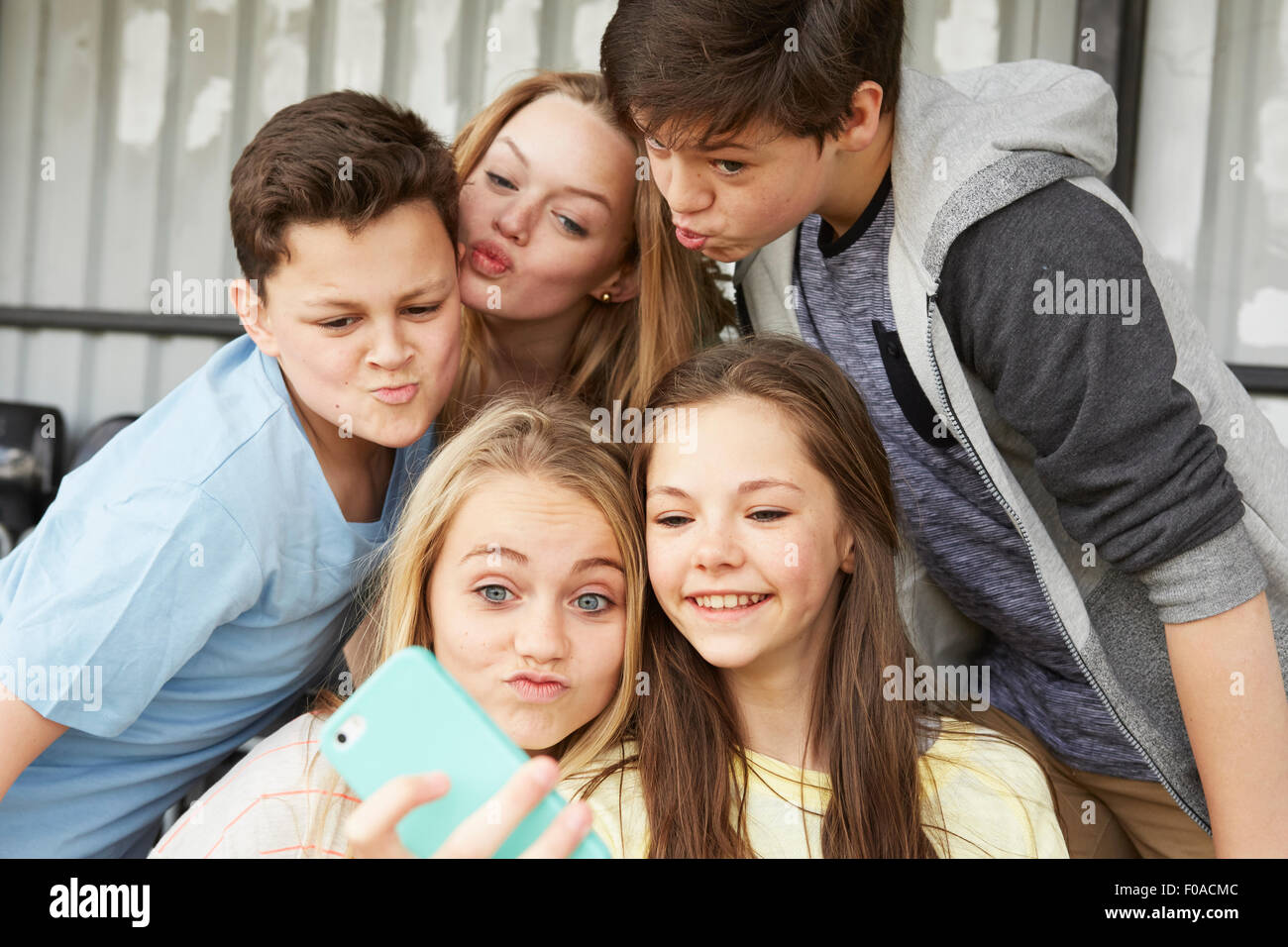 Fünf jungen und Mädchen Grimassen für Smartphone Selfie im Tierheim Stockfoto