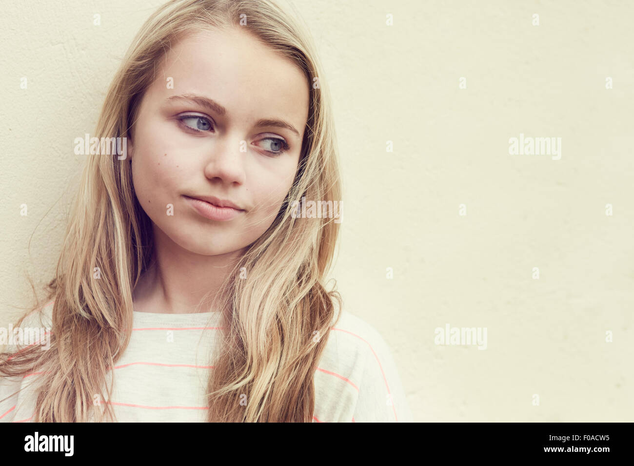 Porträt eines Mädchens mit langen blonden Haaren vor Wand Stockfoto