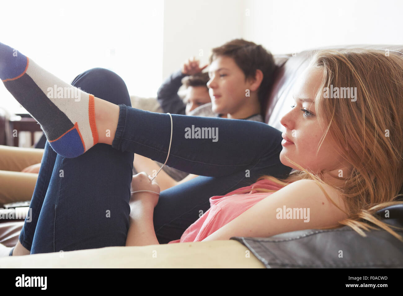 Mädchen und zwei jungen, die vor dem Fernseher vom Sofa aus Stockfoto