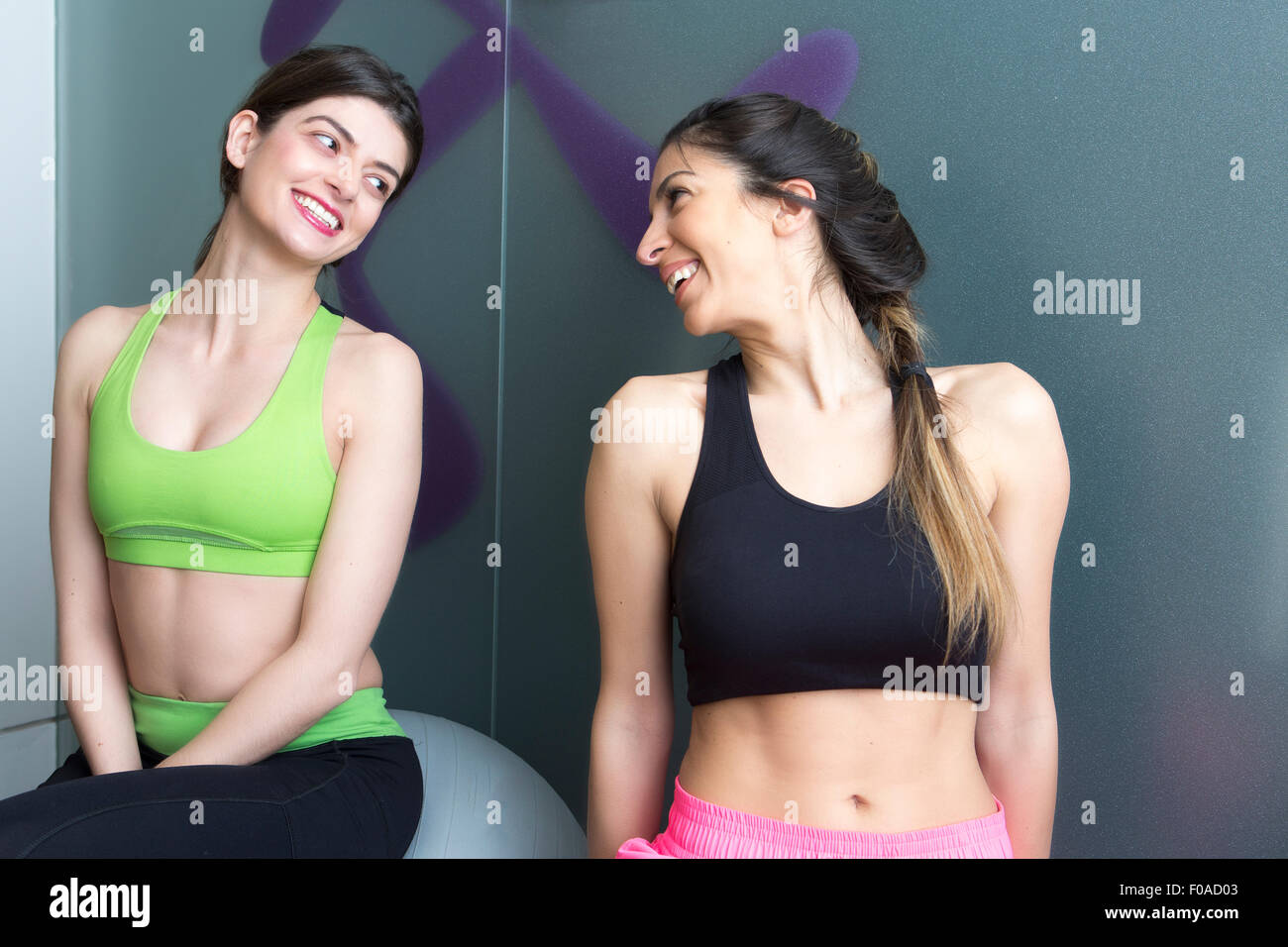 Zwei junge Frauen sahen einander und lächelnd in Fitness-Studio Stockfoto