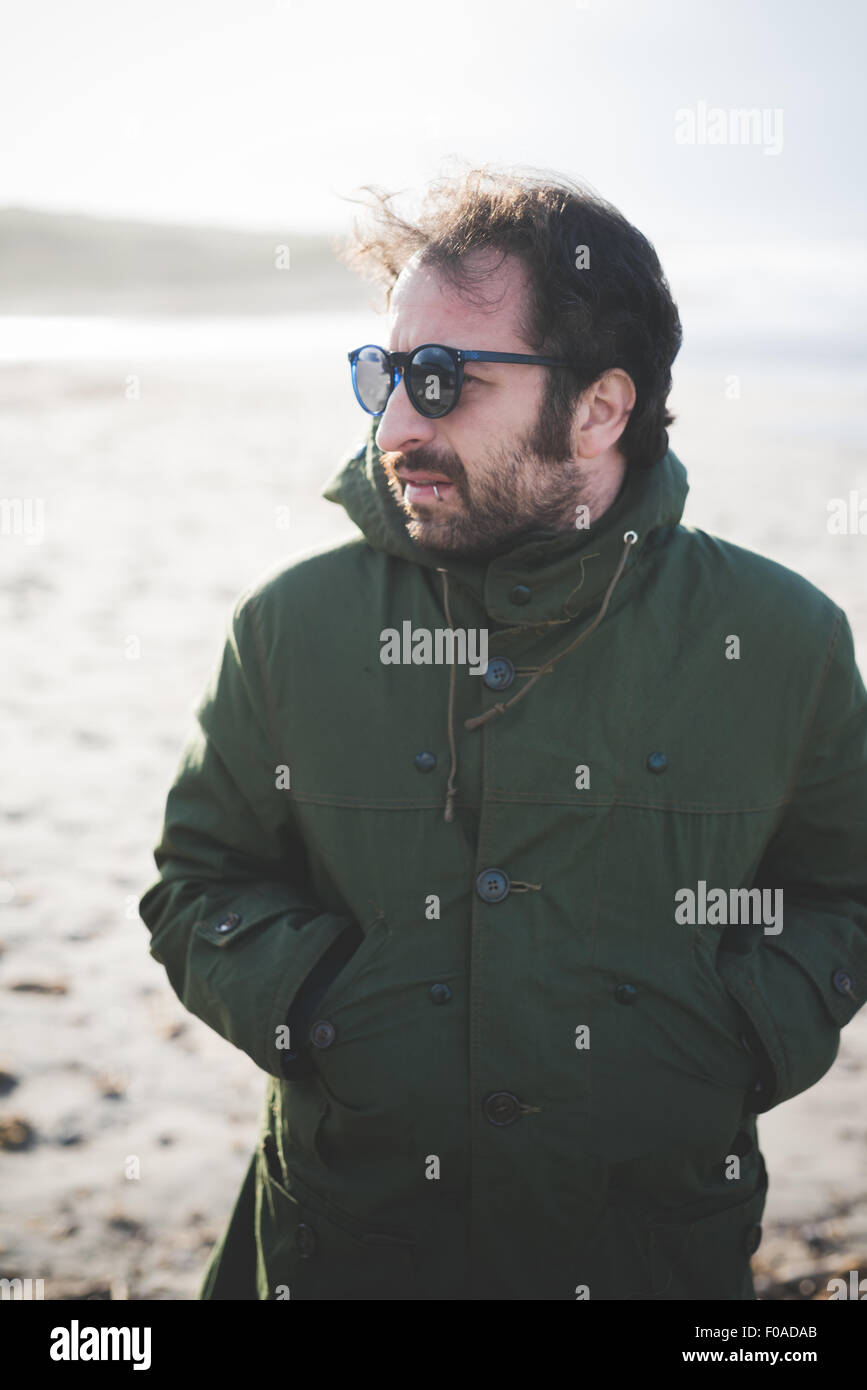 Mitte erwachsener Mann mit Sonnenbrille auf windiger Strand, Sorso, Sassari, Sardinien, Italien Stockfoto
