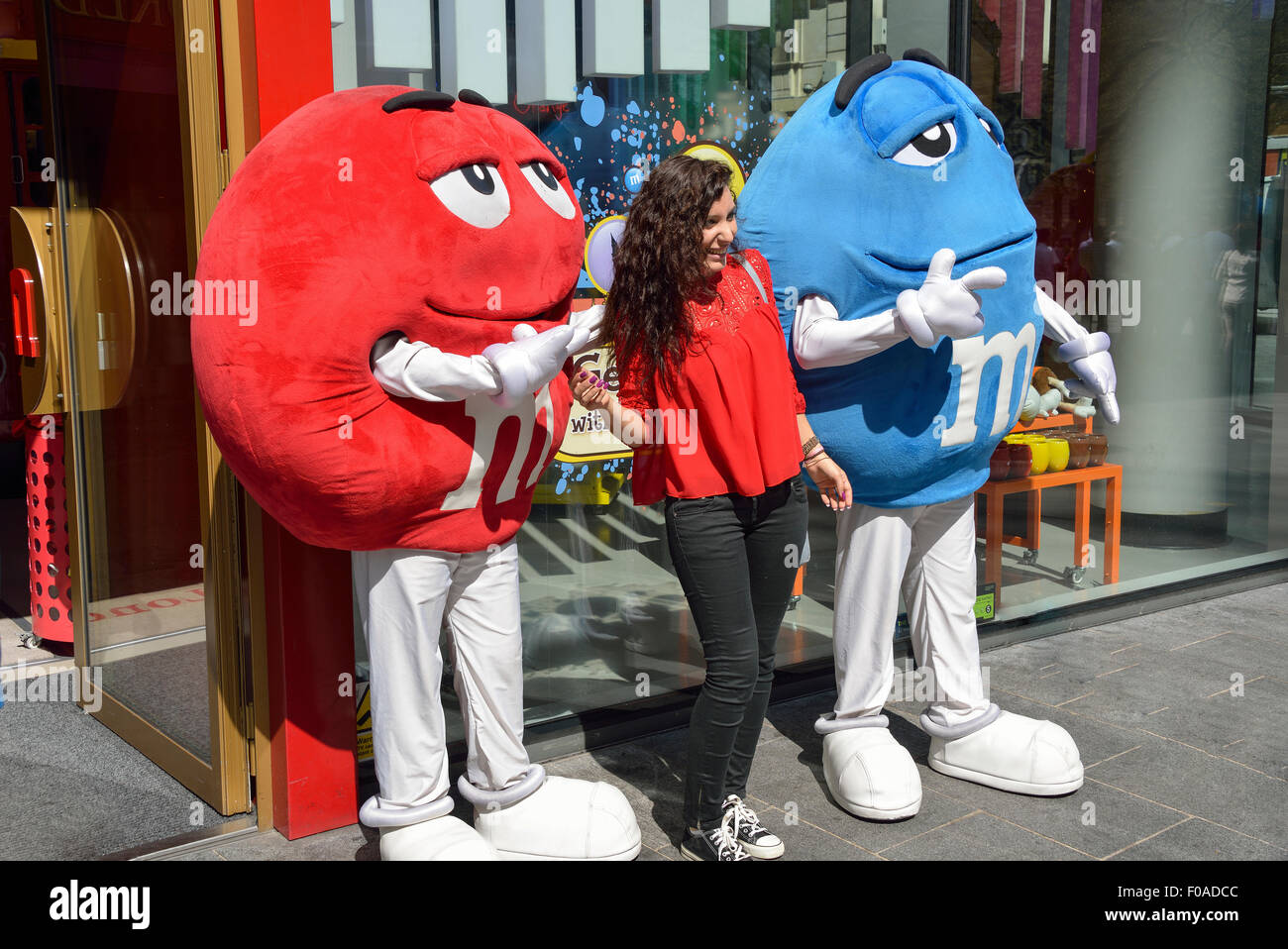 Junge Frau mit Zeichen außerhalb M & M Welt, Leicester Square, West End, City of Westminster, London, Vereinigtes Königreich Stockfoto