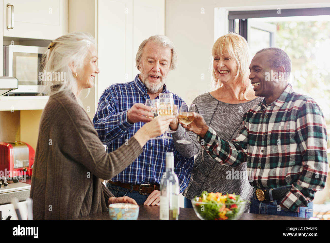 Senioren Freunde Toasten mit Wein in Küche Stockfoto