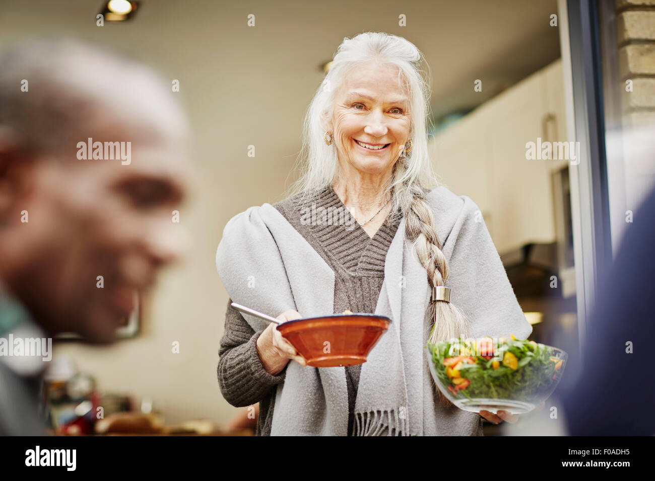 Ältere Frau, die Schüsseln mit Salat außerhalb Stockfoto