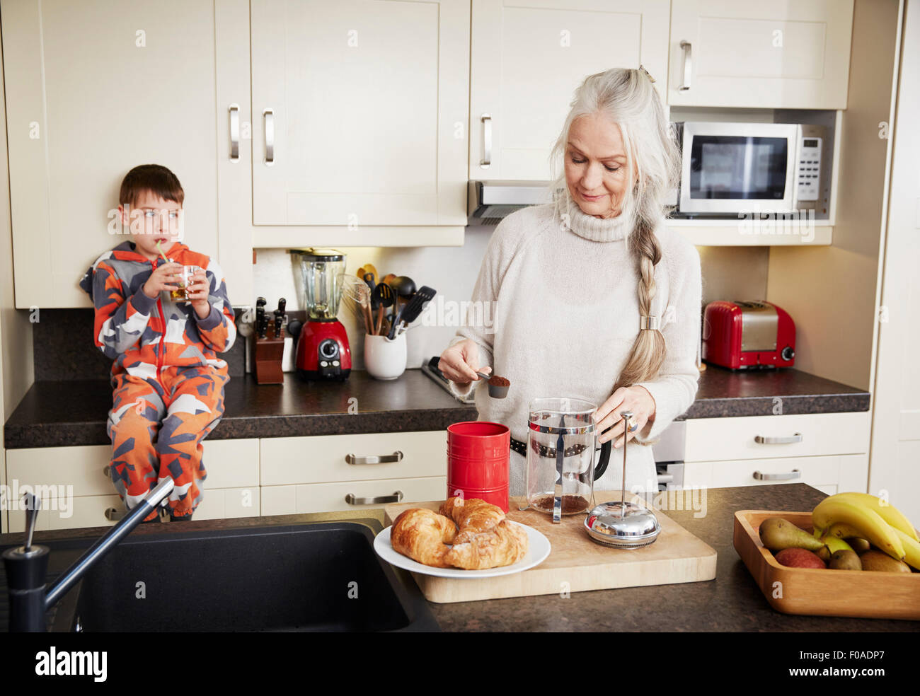 Großmutter, die Zubereitung von Kaffee, Enkel sitzen am Küchentisch Stockfoto