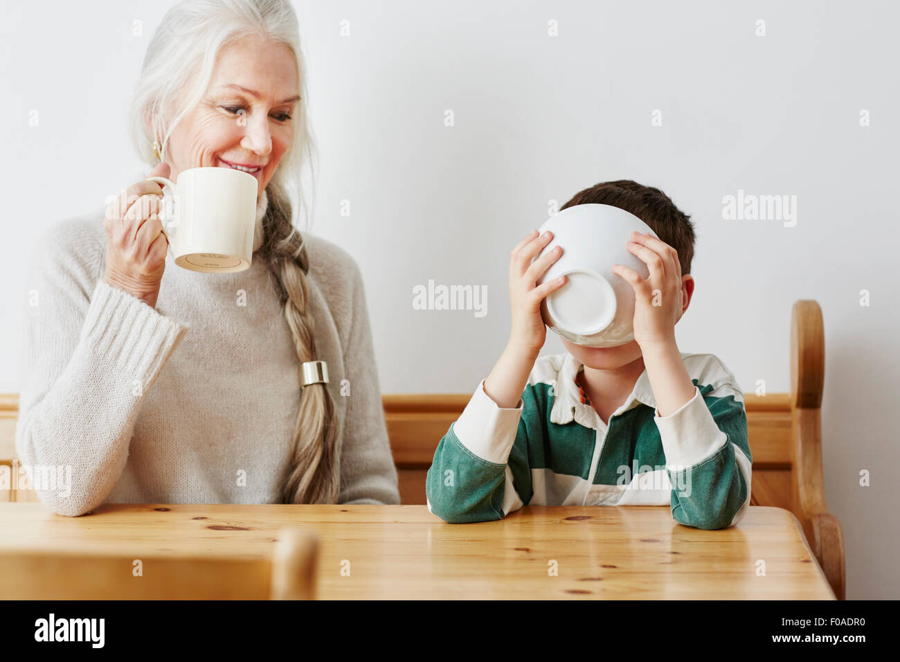 Junge Konsummilch aus Schüssel mit Großmutter Stockfoto