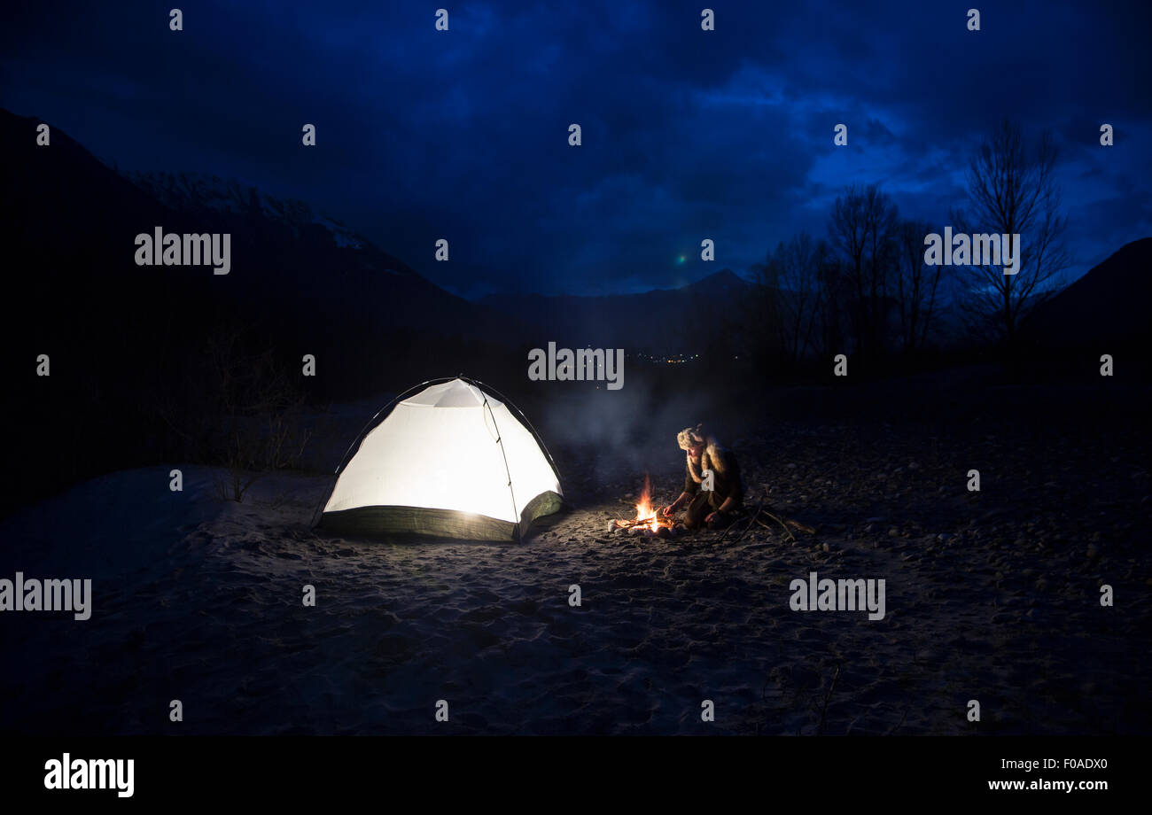 Mann mit Lagerfeuer und Zelt in der Nacht Stockfoto