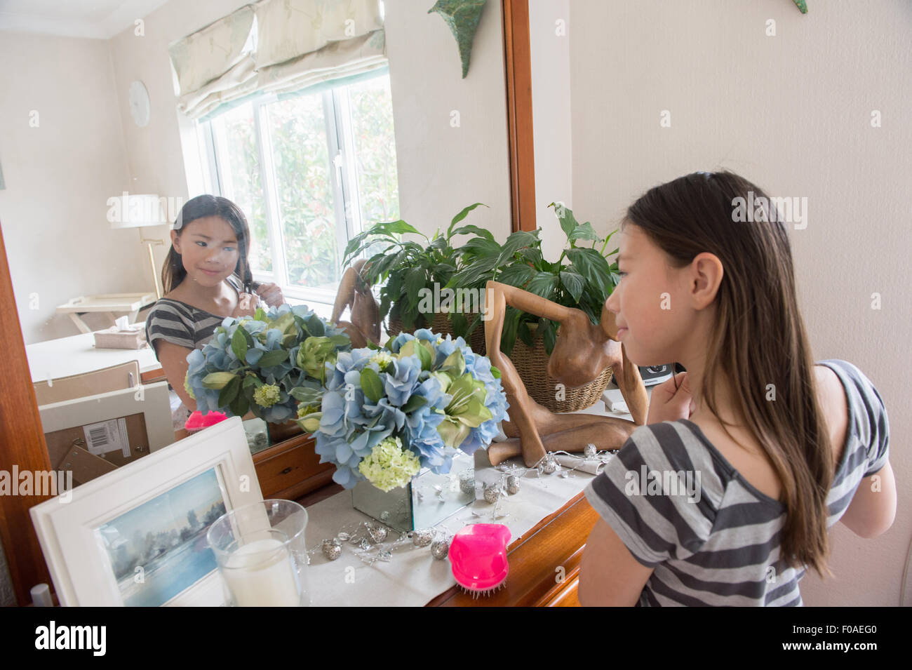 Mädchen im Spiegel und das Hantieren mit ihrem Haar Stockfoto