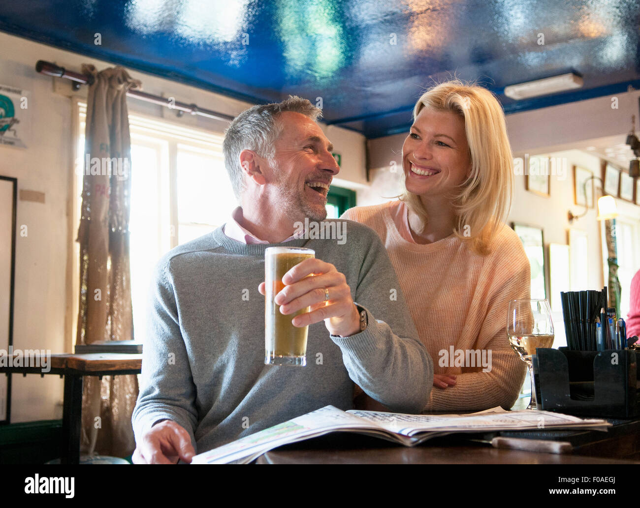 Paar Lachen und Zeitunglesen im pub Stockfoto