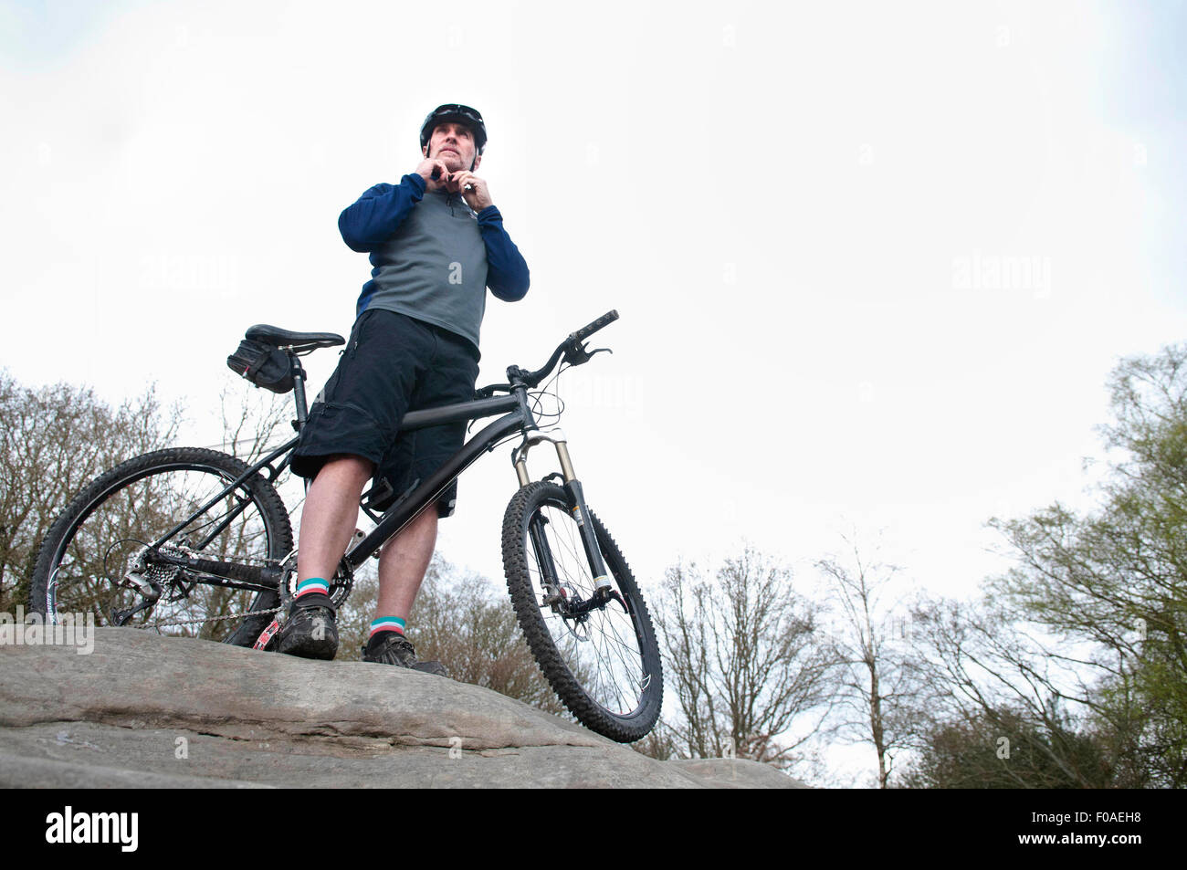 Ältere männliche Mountain Biker Befestigung Helm auf Felsformation Stockfoto