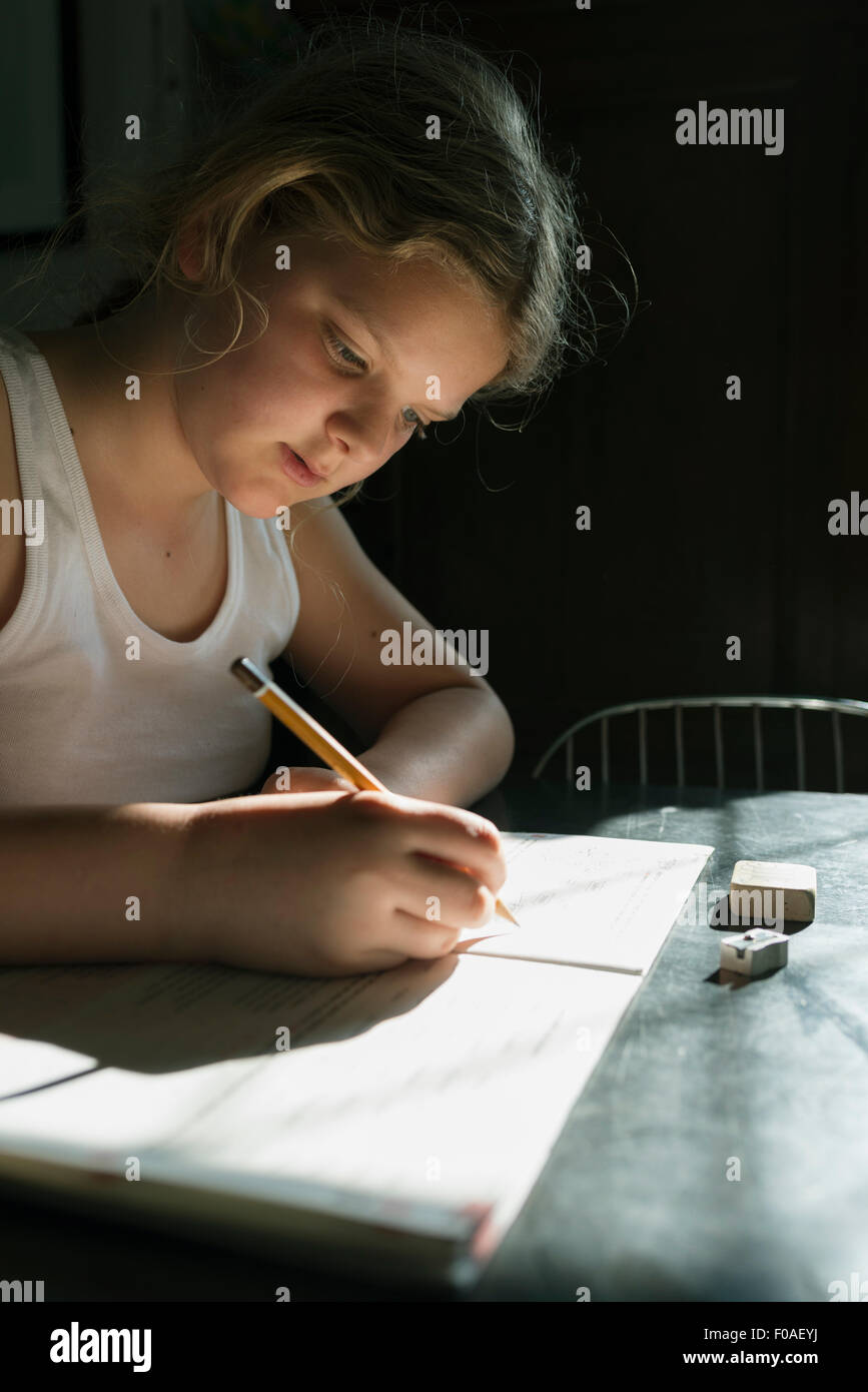 Mädchen, die ihre Hausaufgaben mit Bleistift und Notizbuch Stockfoto