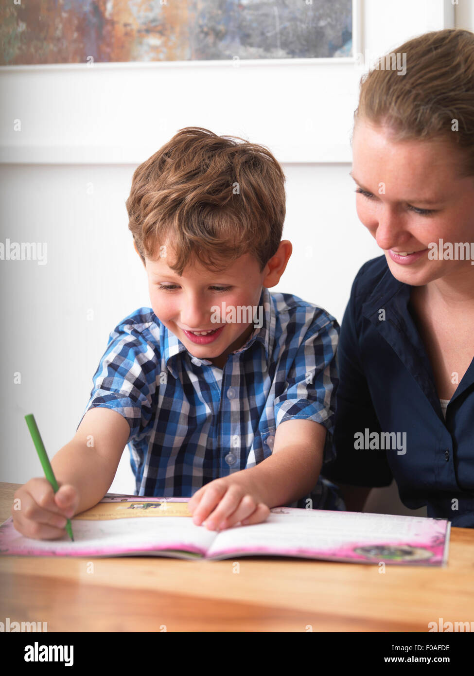 Ein sechsjähriger geholfen mit seinen Hausaufgaben von seiner Mutter zu Hause Stockfoto