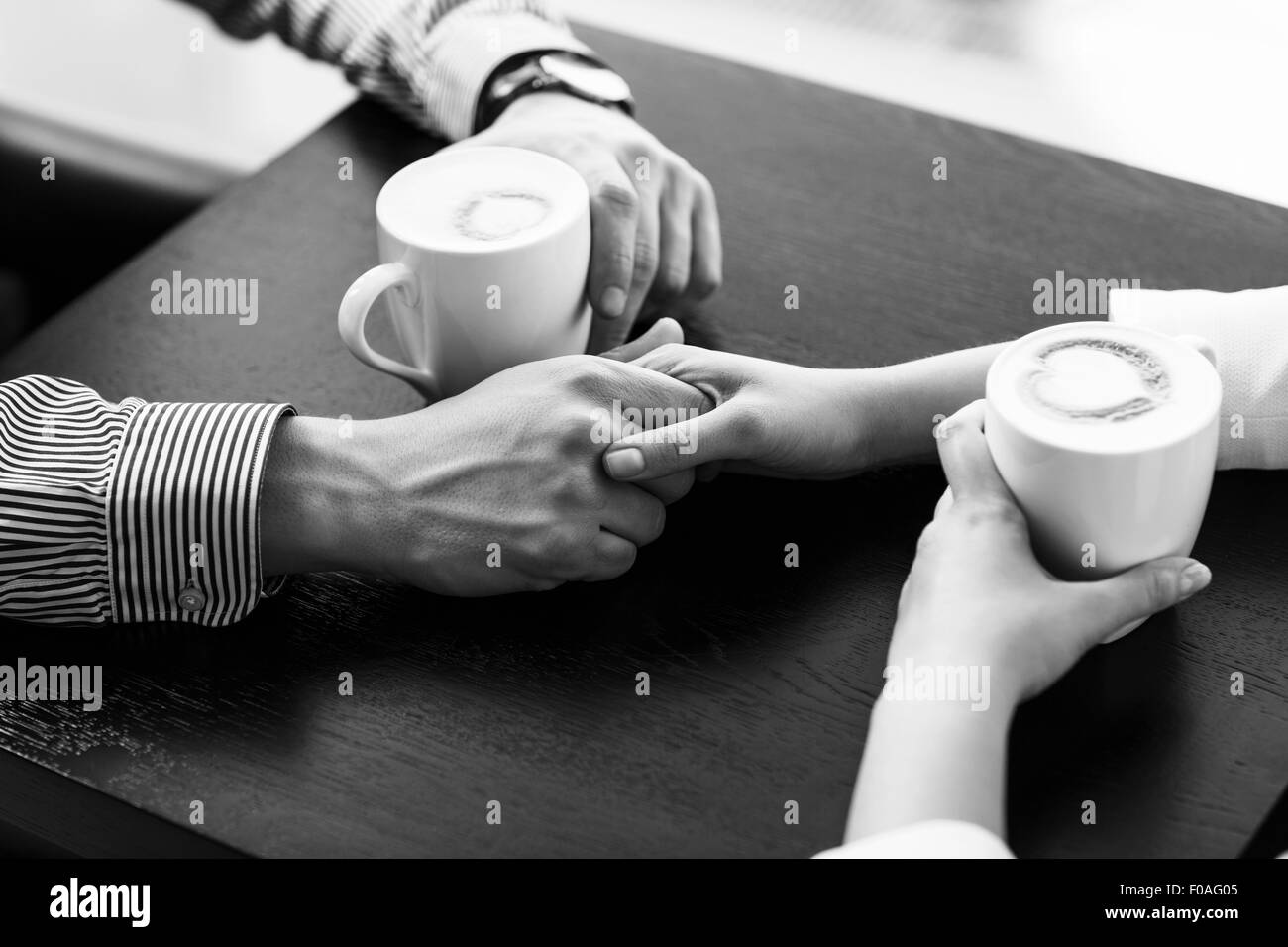 Hände auf dem Tisch halten Tassen Kaffee Stockfoto