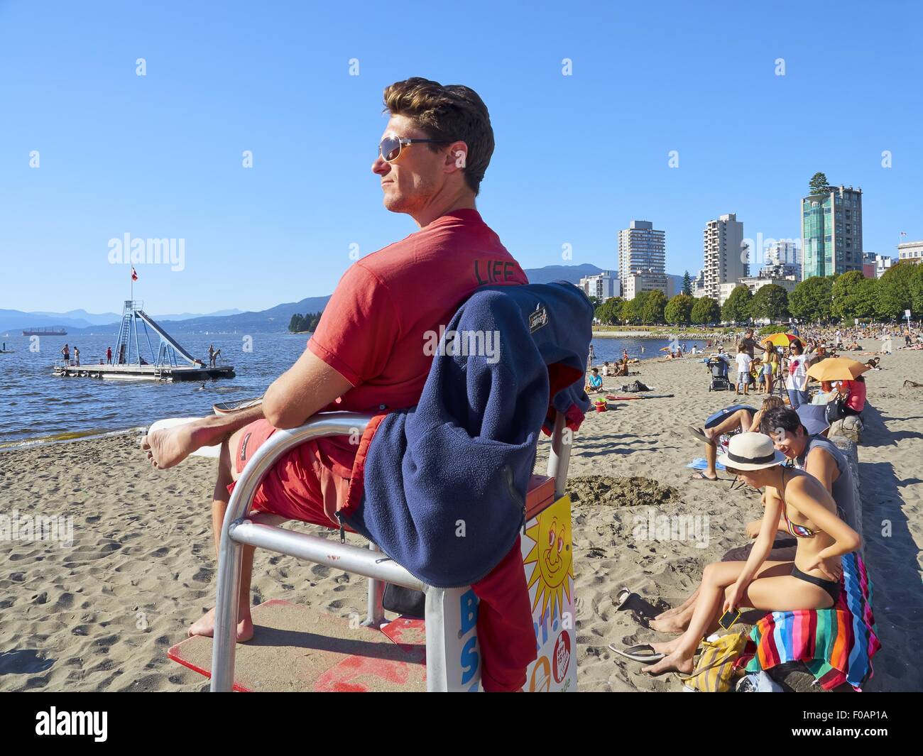 Mann sitzt auf Rettungsschwimmer Stuhl auf Englisch Bay Beach, Vancouver,  Britisch-Kolumbien, Kanada Stockfotografie - Alamy