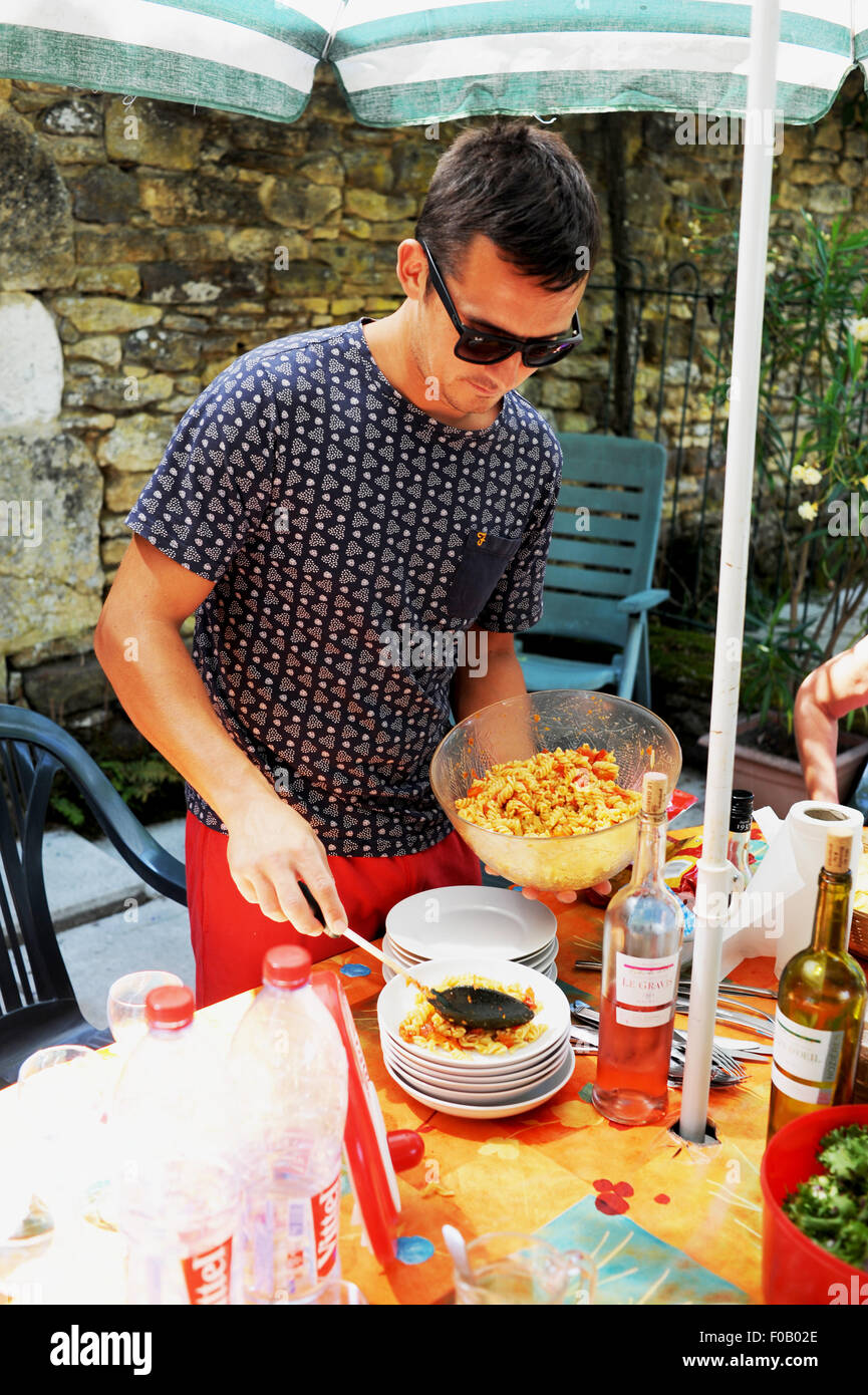 Junger Mann Portion Pasta Mittagessen im Urlaub Ferienhaus in Frayssinet-le-Gelat in der Menge Region Abteilung von Frankreich Midi-Pyrenees Foto Stockfoto