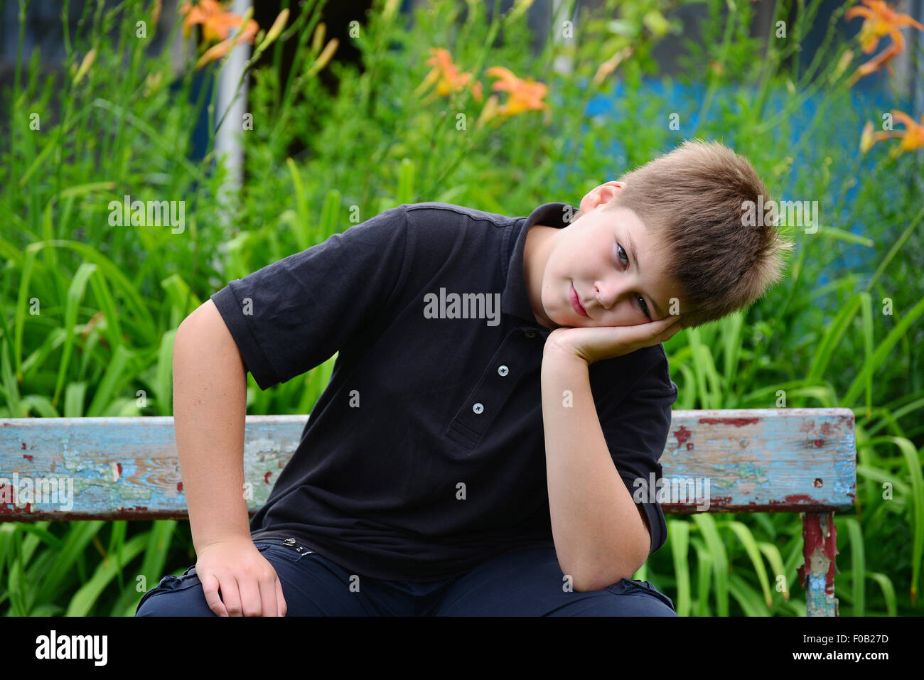 Ein Teenage Junge sitzt auf einer Bank Stockfoto