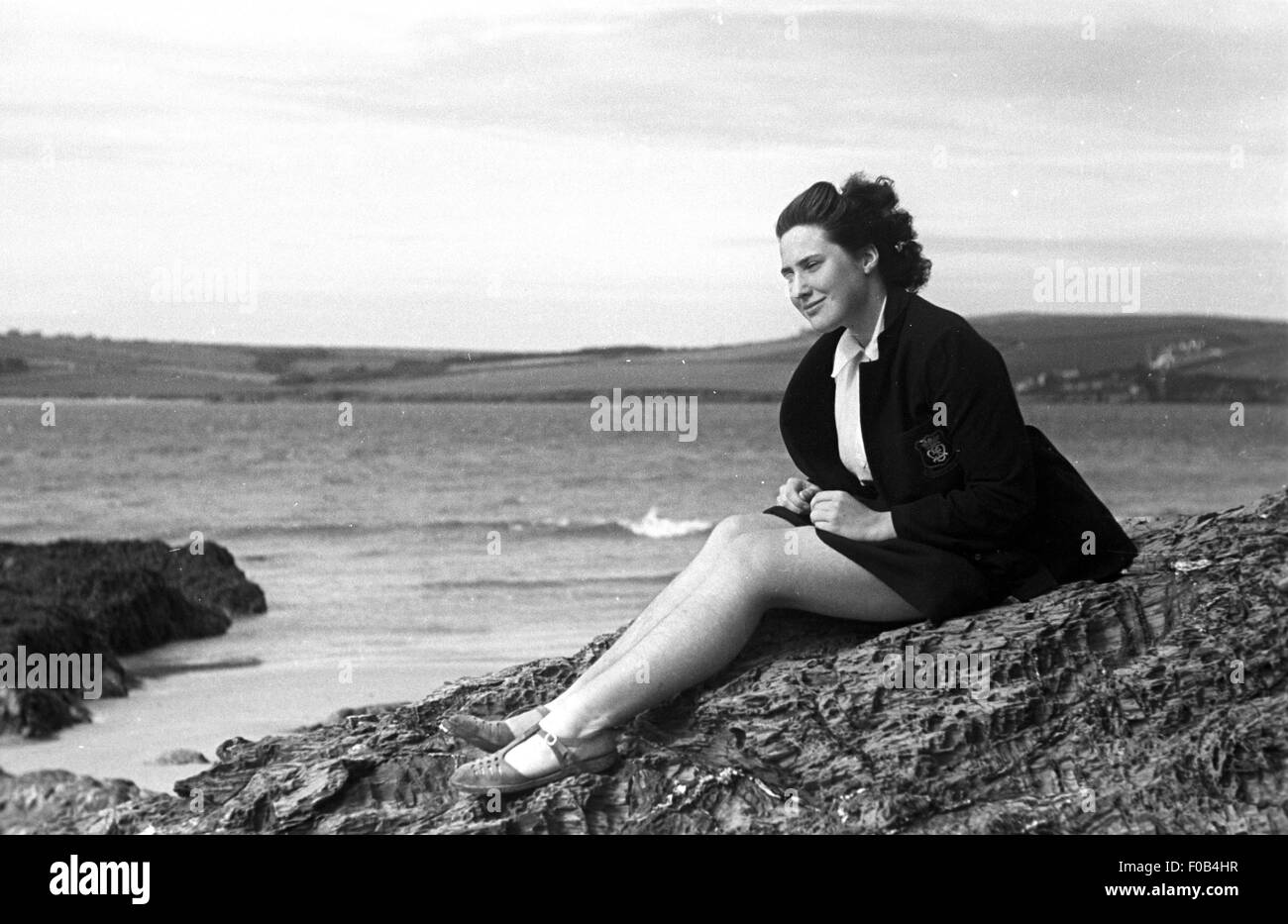 Eine junge Dame, sitzen auf den Felsen am Meer. Stockfoto