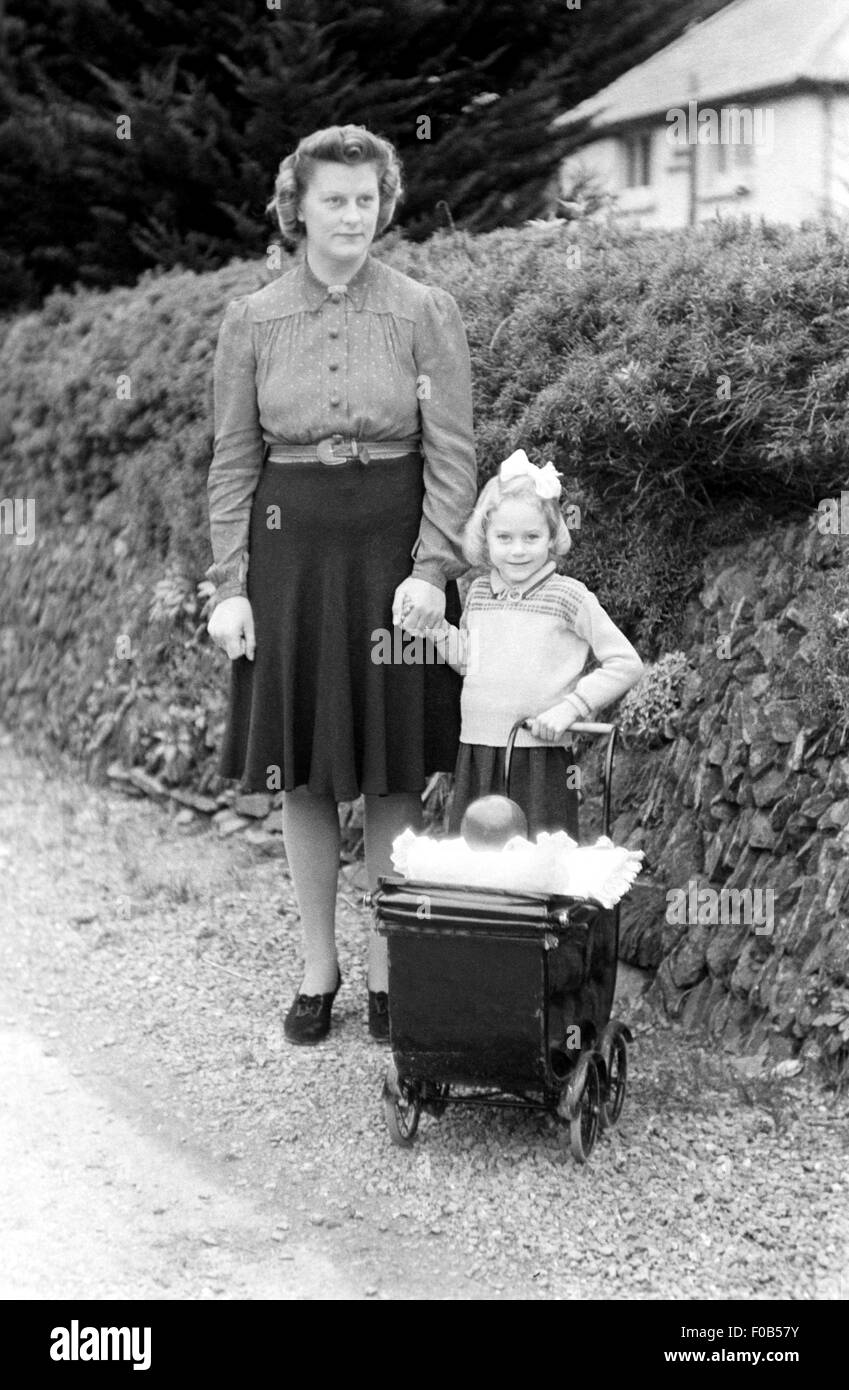 Eine Mutter und Tochter mit dem Kind Puppen Kinderwagen. Stockfoto