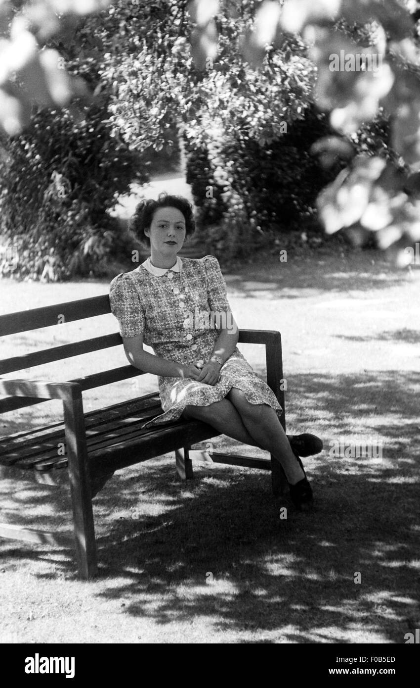 Porträt einer Frau sitzen auf einer Bank in einem Garten Stockfoto