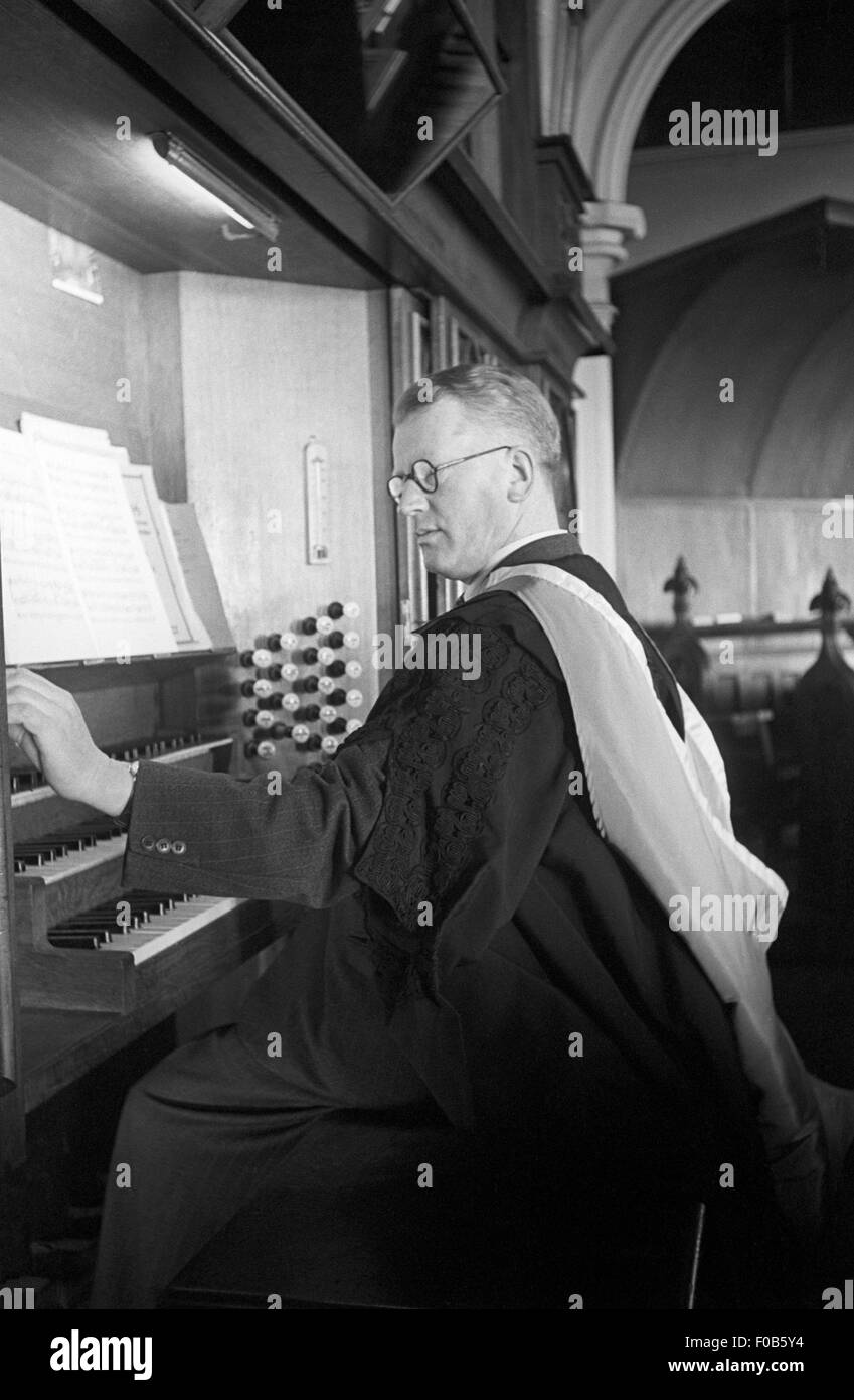 Ein elegant gekleideter Mann in Roben der Orgel in der Kapelle. Stockfoto