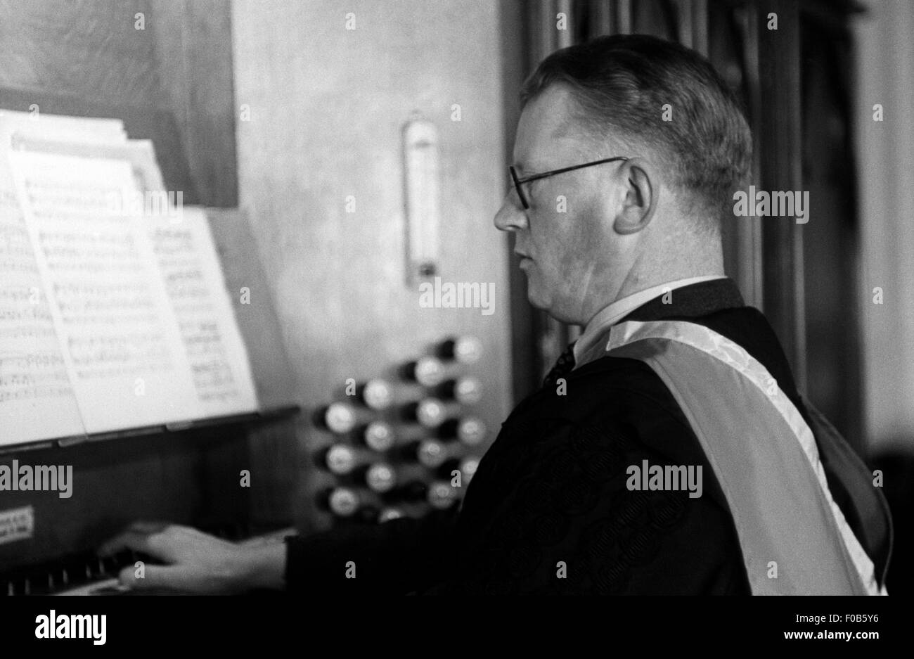 Ein elegant gekleideter Mann in Roben der Orgel in der Kapelle. Stockfoto