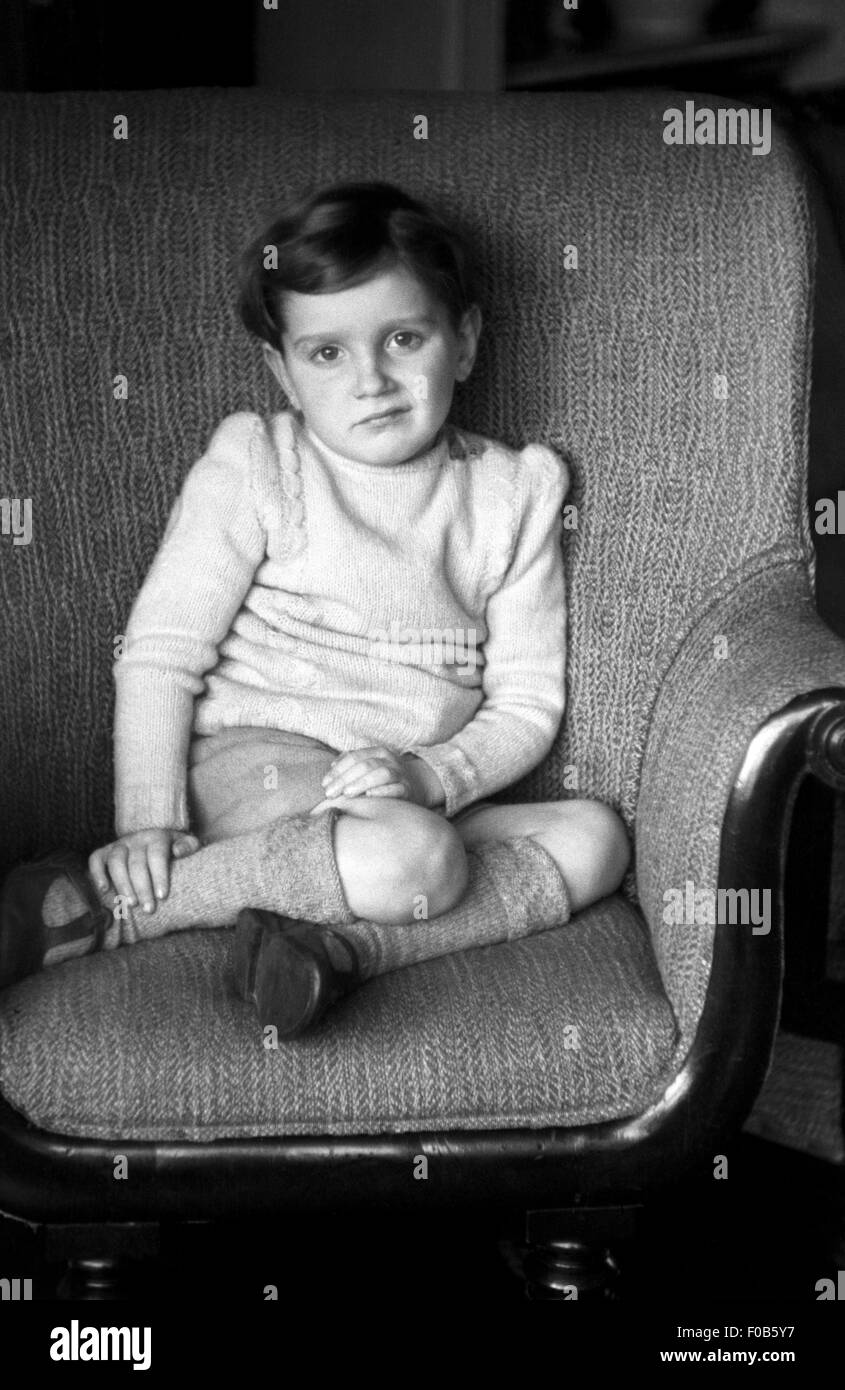 Dunklen Haaren Kind sitzt auf einem Stuhl. Stockfoto