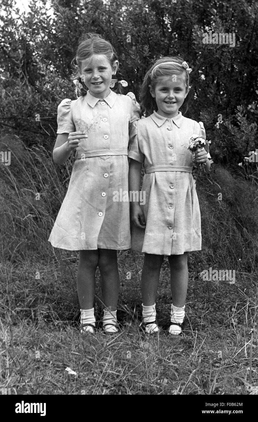 Zwei kleine Mädchen im Partnerlook mit Blumen. Stockfoto