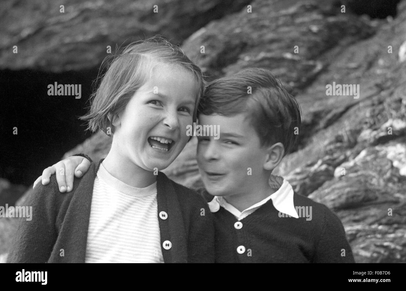 Ein junger Bruder und ältere Schwester vor den Felsen am Meer Stockfoto