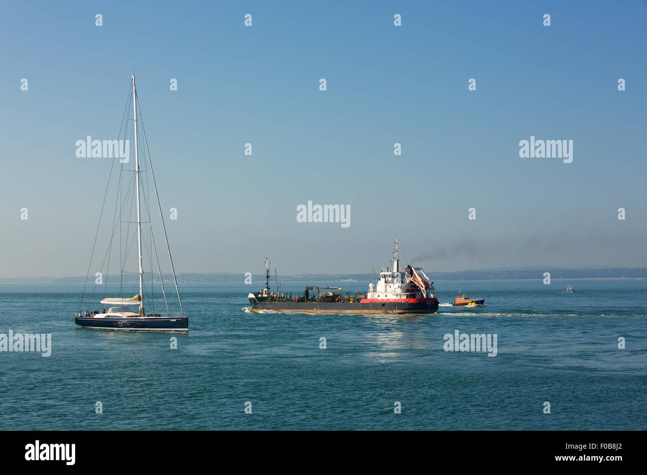 Kleinen Öltanker, vorbei an einer Luxusyacht am Eingang zum Hafen von Portsmouth. Stockfoto