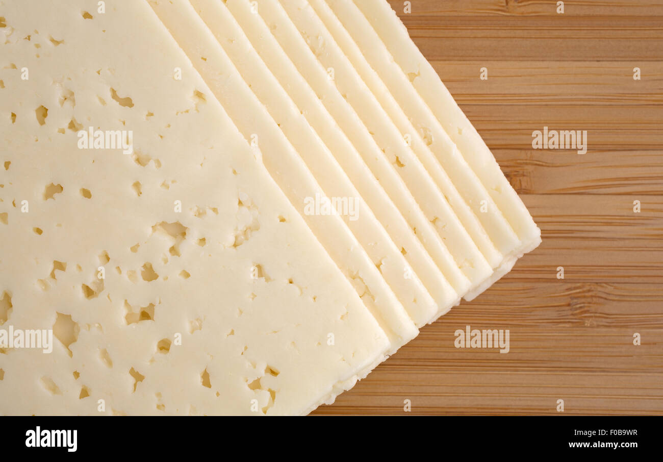 Obere Winkel Blick auf mehrere Scheiben Havarti Käse auf ein Holz Schneidebrett mit natürlichem Licht beleuchtet. Stockfoto