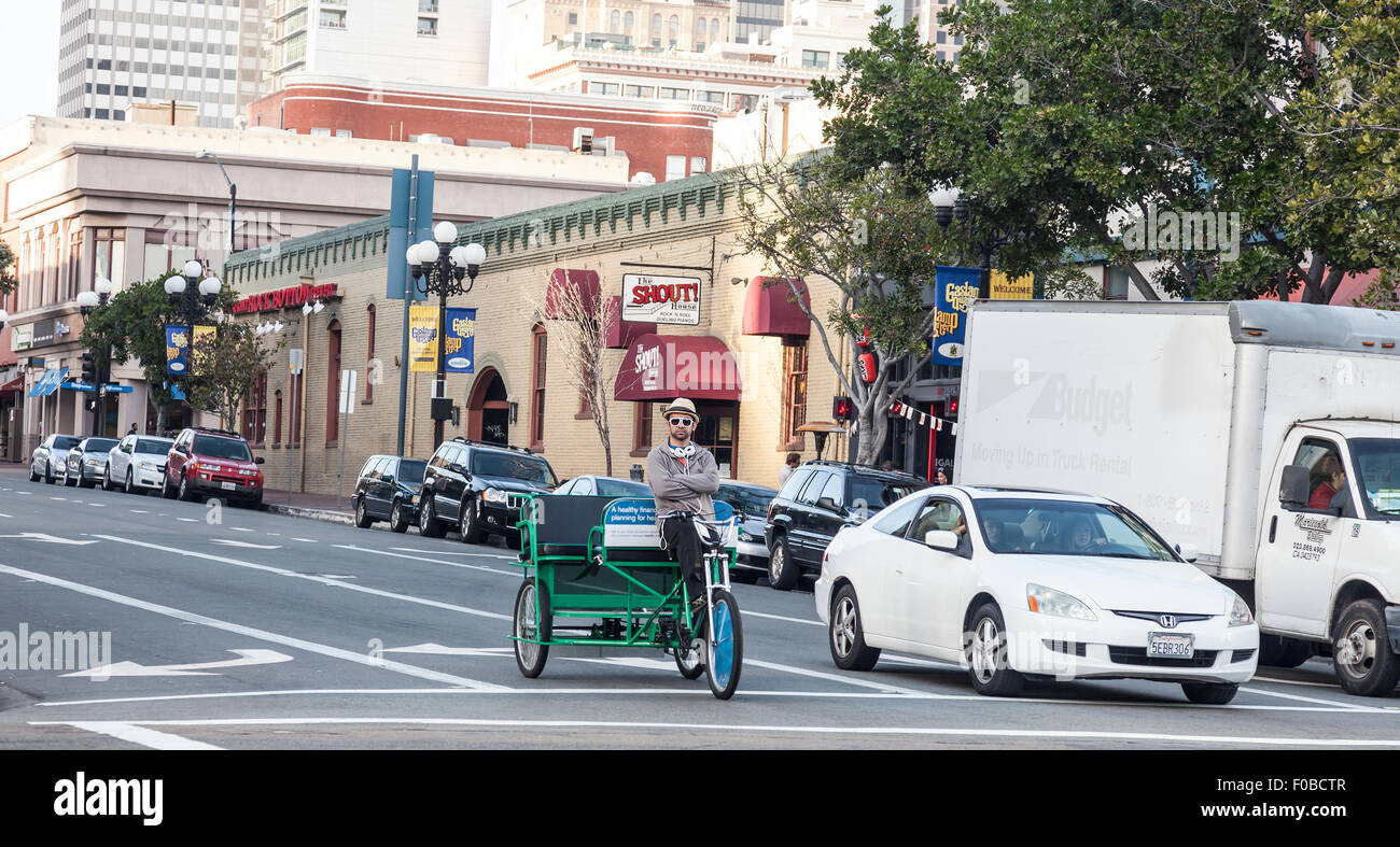 Zyklus-Rikscha-Fahrer entspannt während an einer Kreuzung auf der 4th Avenue & Market Street, San Diego in der Nähe von The Shout House gestoppt.  USA Stockfoto