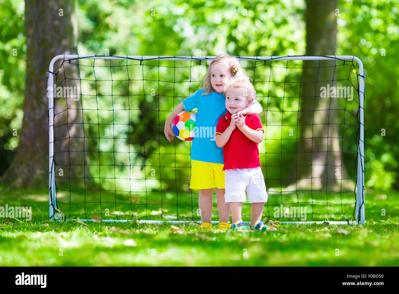 Zwei glückliche Kinder spielen Fußball im Freien im Schulhof. Kinder spielen Fußball. Aktiv Sport für Vorschulkind. Stockfoto