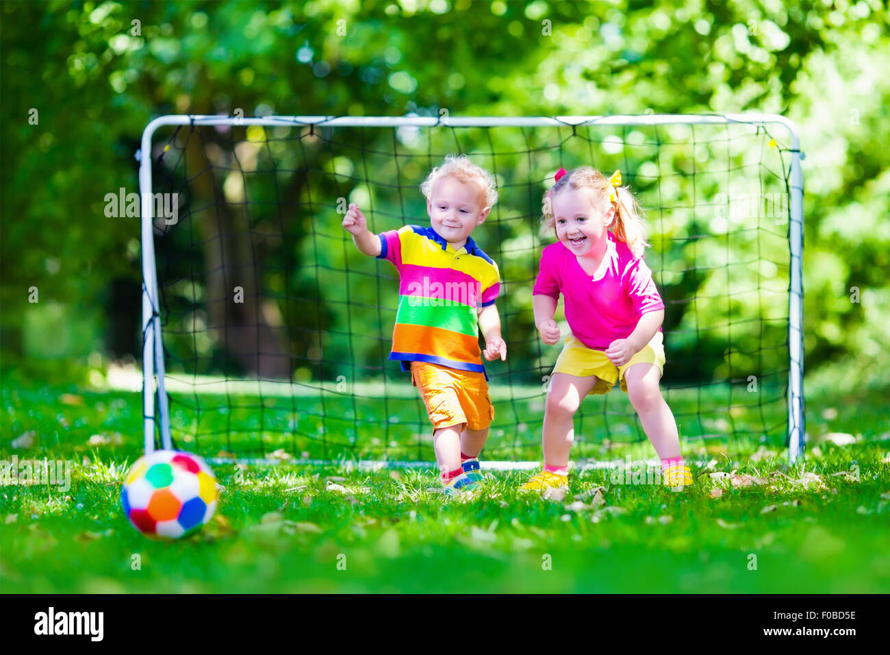 Zwei glückliche Kinder spielen Fußball im Freien im Schulhof. Kinder spielen Fußball. Aktiv Sport für Vorschulkind. Stockfoto