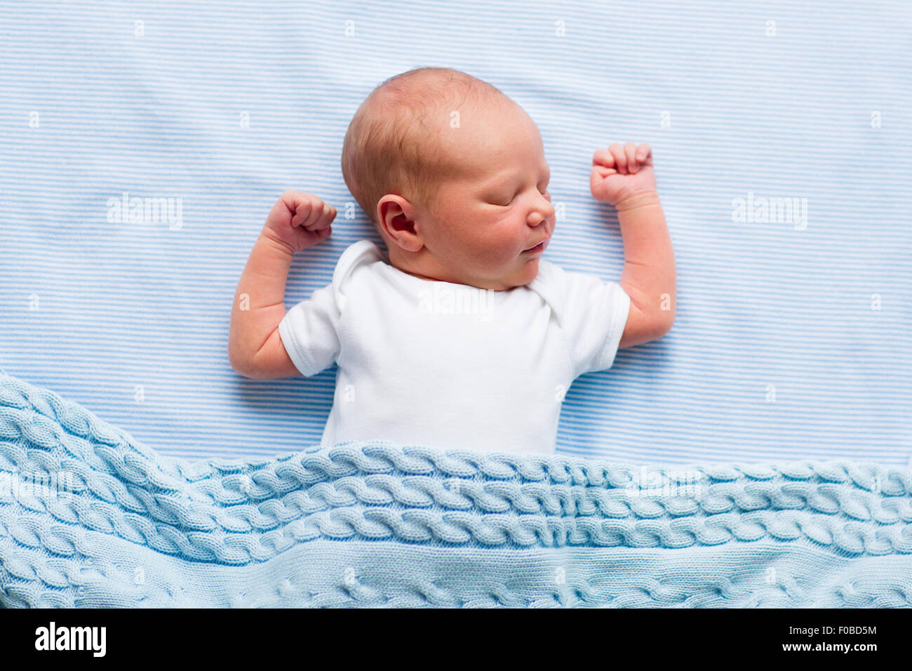 Neugeborenes Baby junge im Bett. Neues Kind geboren, unter einer blauen gestrickte Decke schlafen. Kinder schlafen. Bettwäsche für Kinder. Säugling Nickerchen Stockfoto