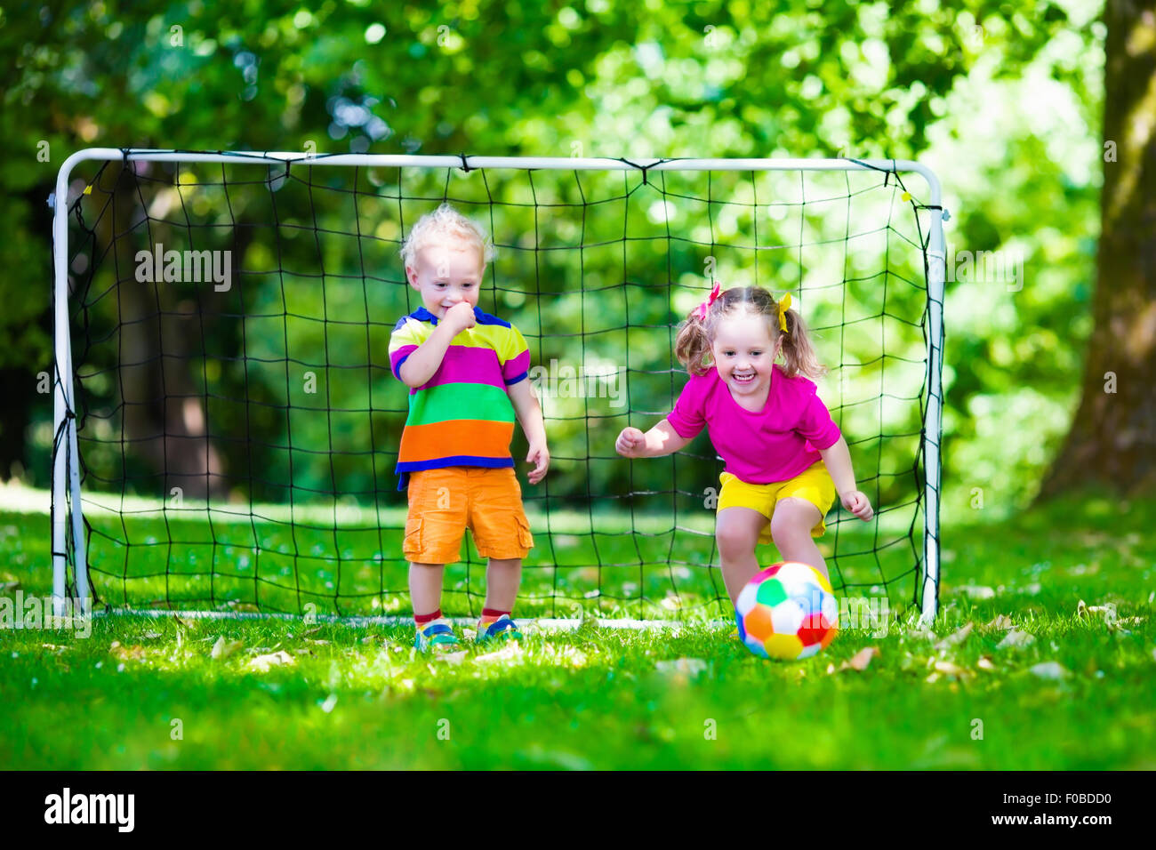 Zwei glückliche Kinder spielen Fußball im Freien im Schulhof. Kinder spielen Fußball. Aktiv Sport für Vorschulkind. Stockfoto