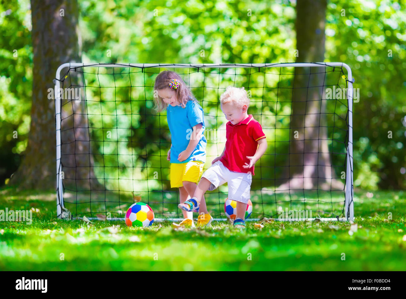 Zwei glückliche Kinder spielen Fußball im Freien im Schulhof. Kinder spielen Fußball. Aktiv Sport für Vorschulkind. Stockfoto
