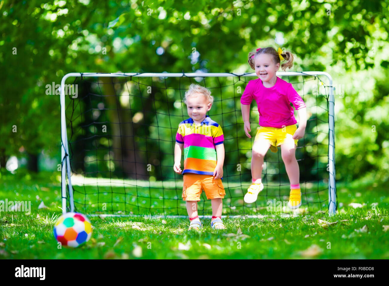 Zwei glückliche Kinder spielen Fußball im Freien im Schulhof. Kinder spielen Fußball. Aktiv Sport für Vorschulkind. Stockfoto