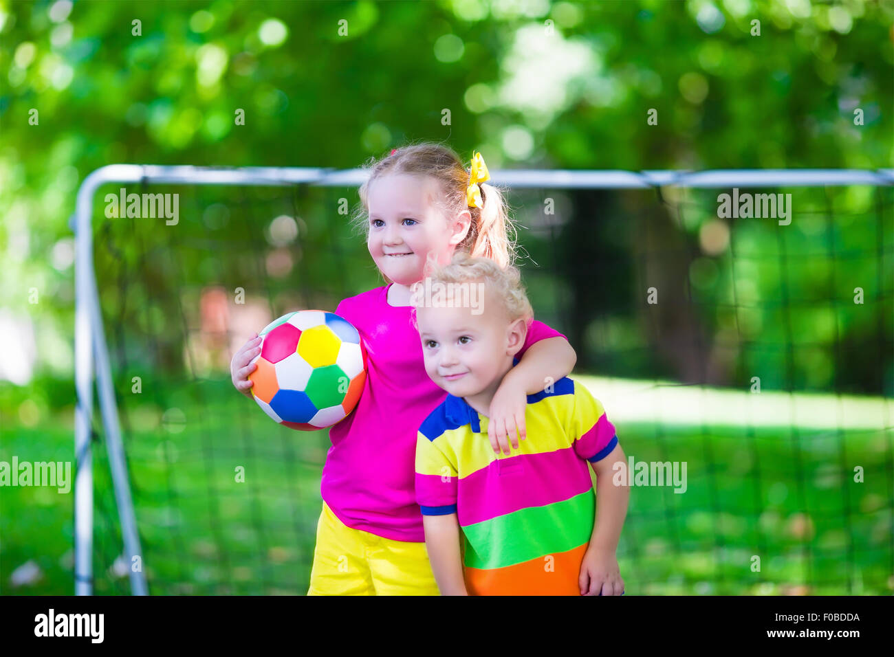 Zwei glückliche Kinder spielen Fußball im Freien im Schulhof. Kinder spielen Fußball. Aktiv Sport für Vorschulkind. Stockfoto