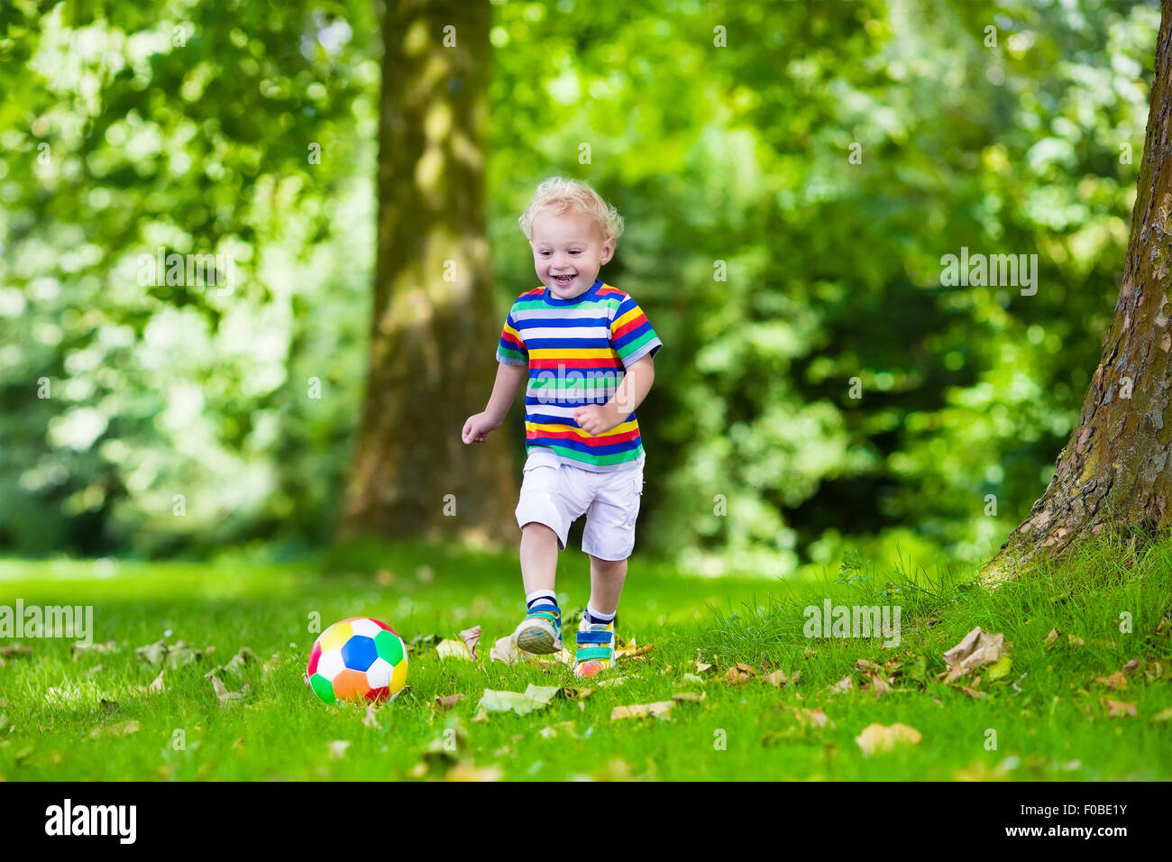 Glückliches Kind spielen Fußball im Freien im Schulhof. Kinder spielen Fußball. Aktiv Sport für Vorschulkind. Stockfoto