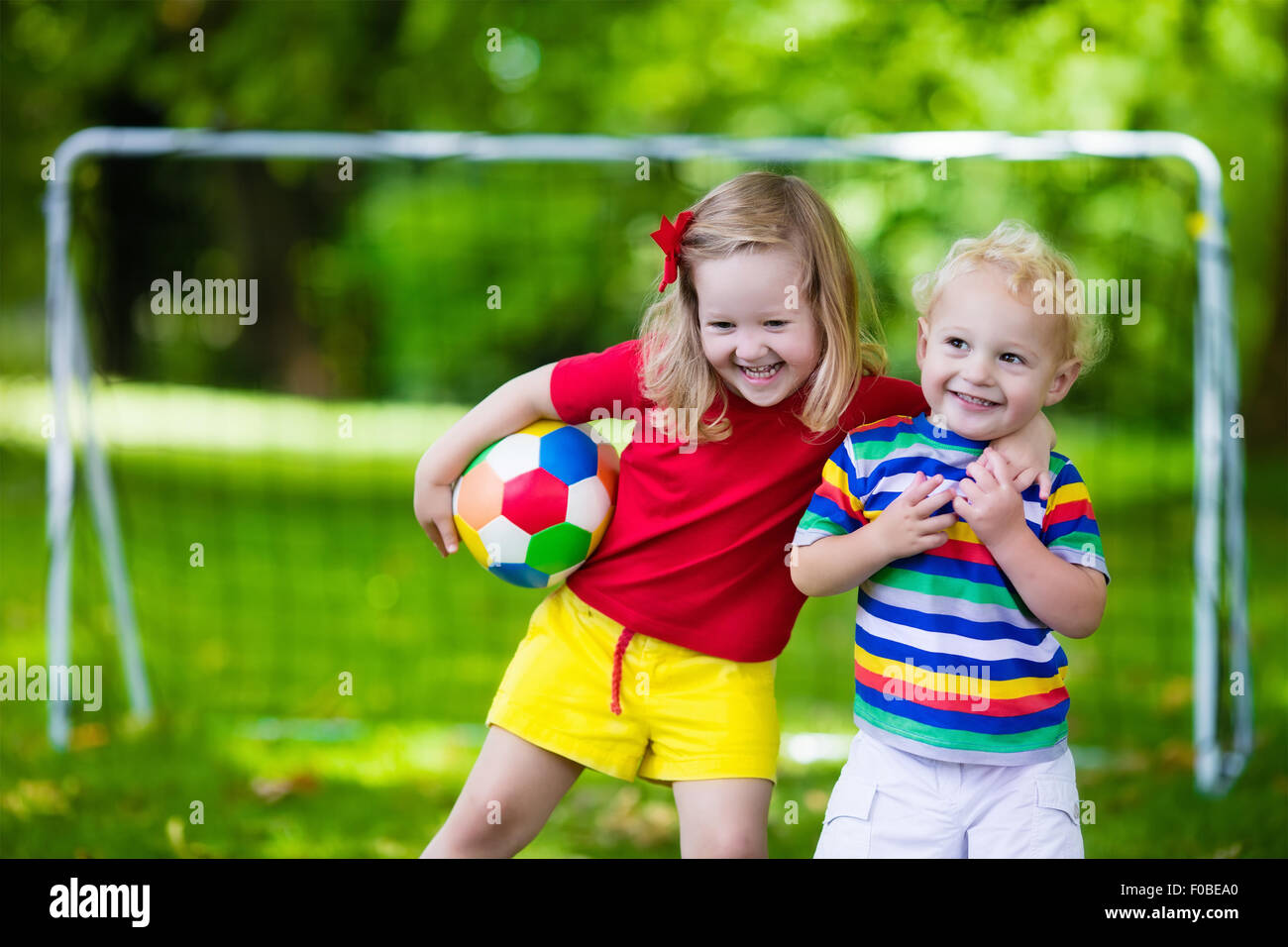 Zwei glückliche Kinder spielen Fußball im Freien im Schulhof. Kinder spielen Fußball. Aktiv Sport für Vorschulkind. Stockfoto