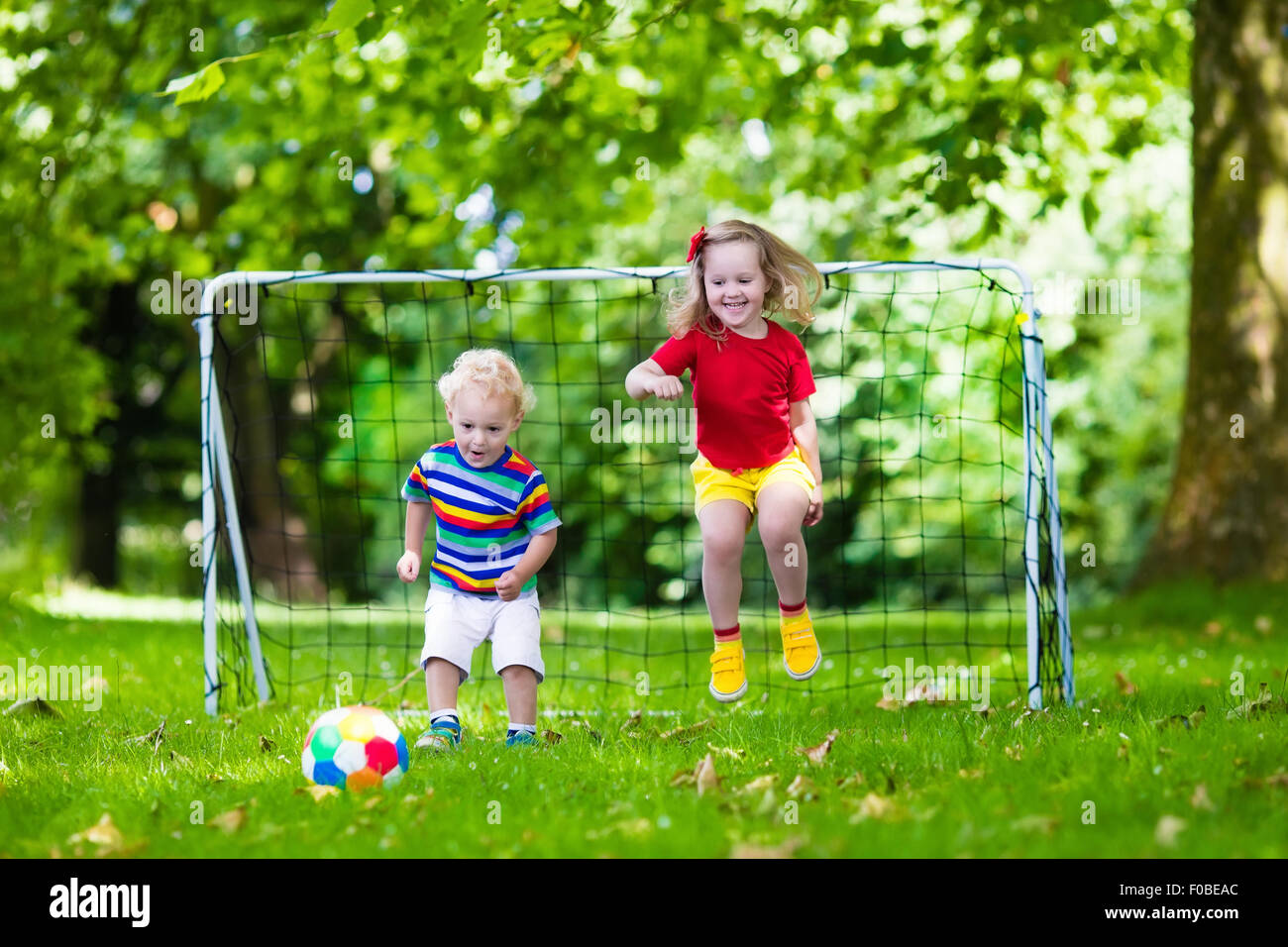 Zwei glückliche Kinder spielen Fußball im Freien im Schulhof. Kinder spielen Fußball. Aktiv Sport für Vorschulkind. Stockfoto