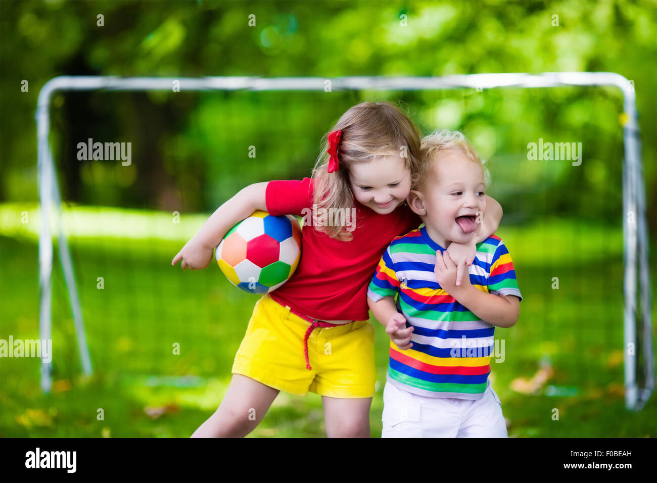 Zwei glückliche Kinder spielen Fußball im Freien im Schulhof. Kinder spielen Fußball. Aktiv Sport für Vorschulkind. Stockfoto