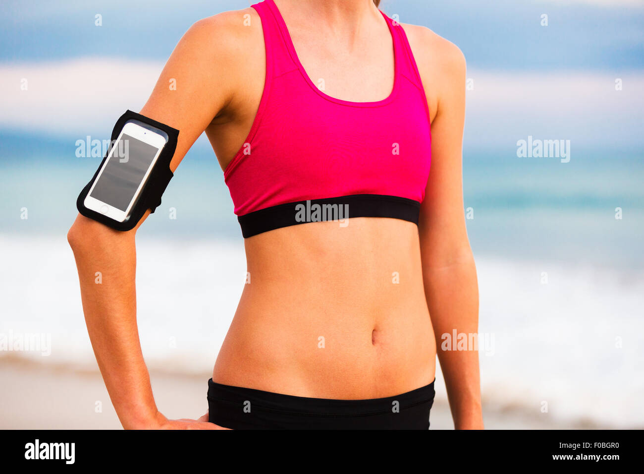 Junge Fitness Frau mit Smartphone Ready for Training. Fitness-Technologie-Konzept. Stockfoto