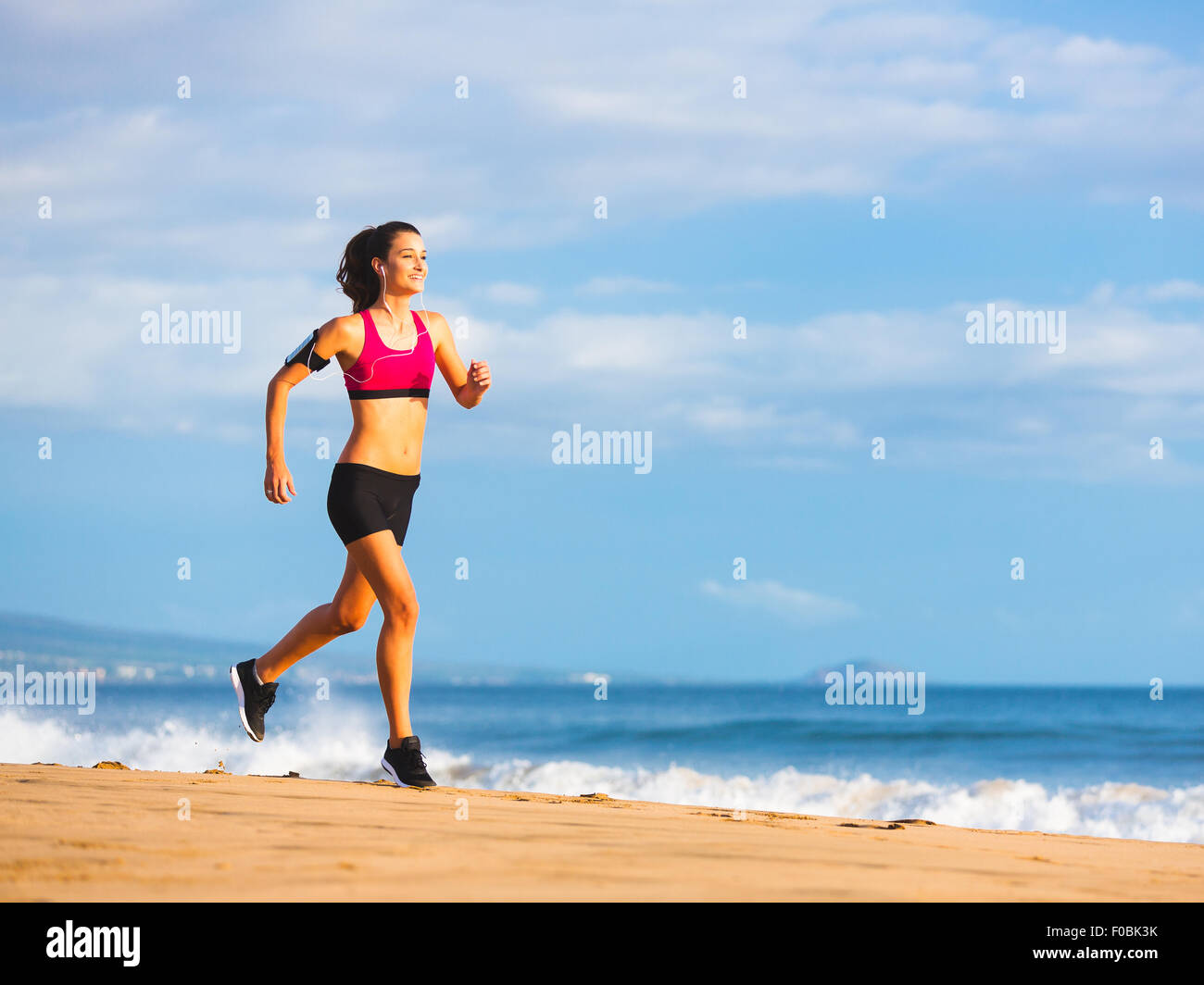 Fitness-Frau läuft am Meer bei Sonnenuntergang Stockfoto