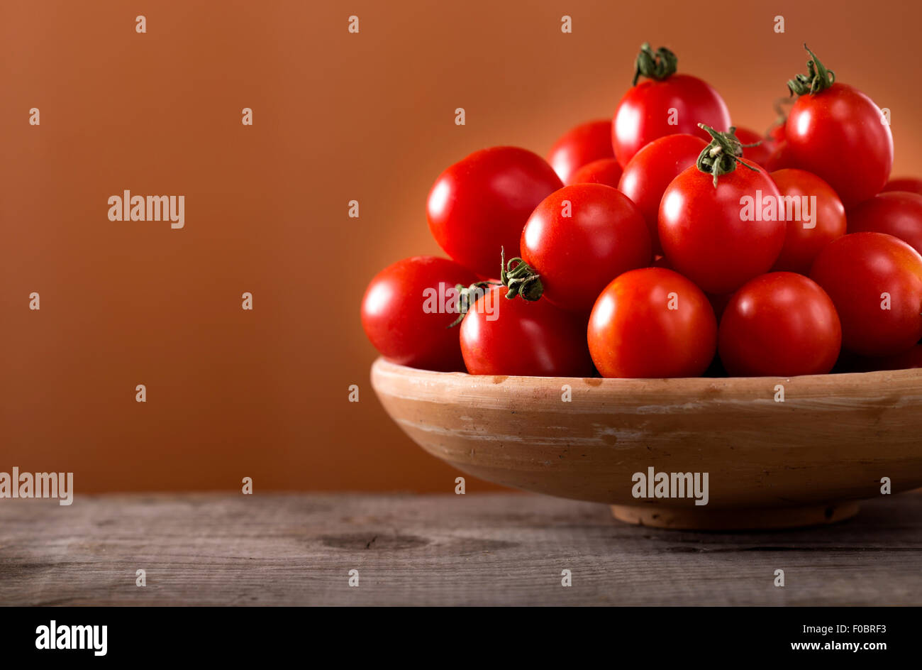Frische Tomaten in einer Schüssel auf alten Holztisch Stockfoto