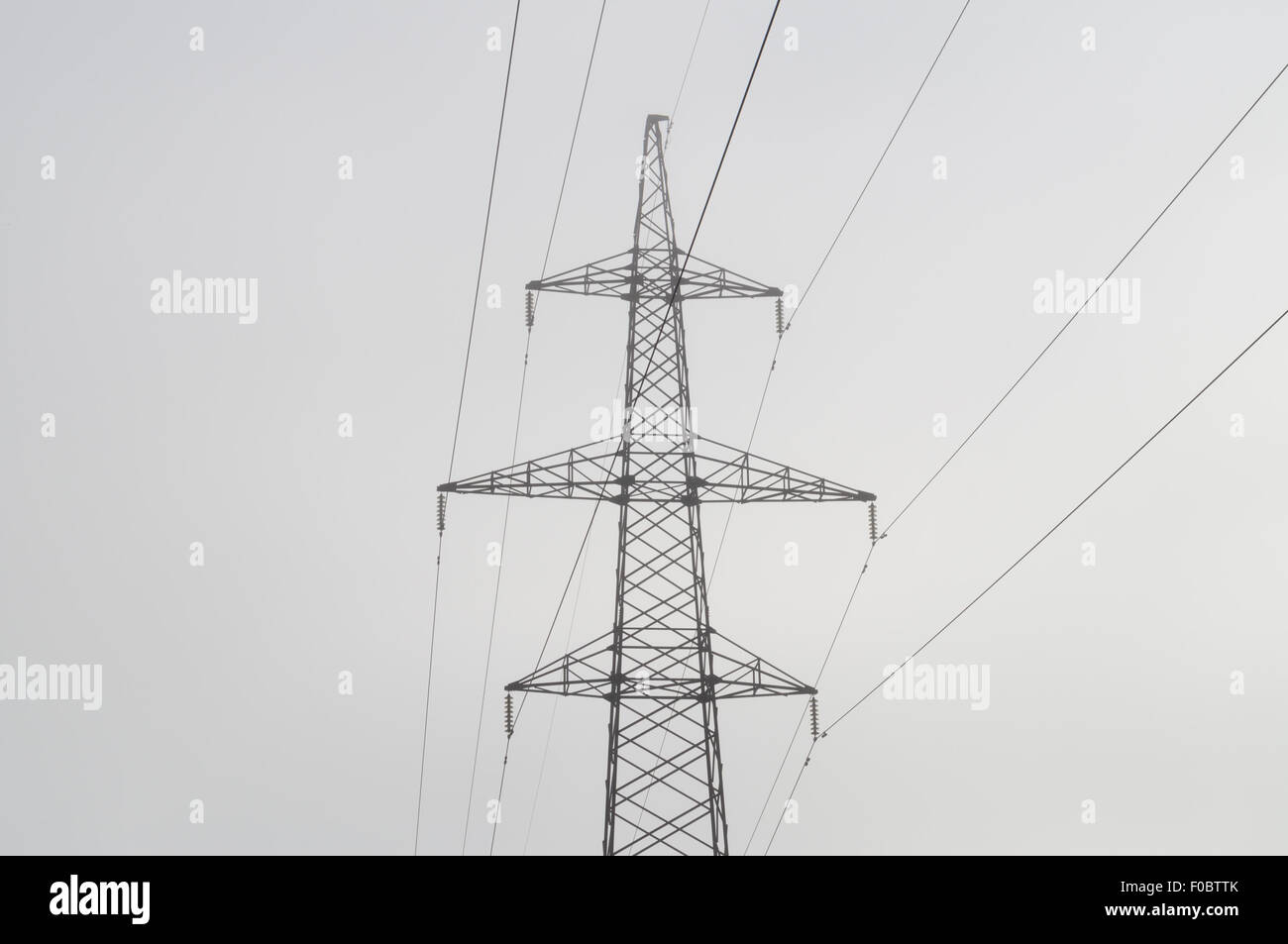 Elektrische Hochspannung macht Post, abstrakte Ansicht in Morgen Nebel Stockfoto
