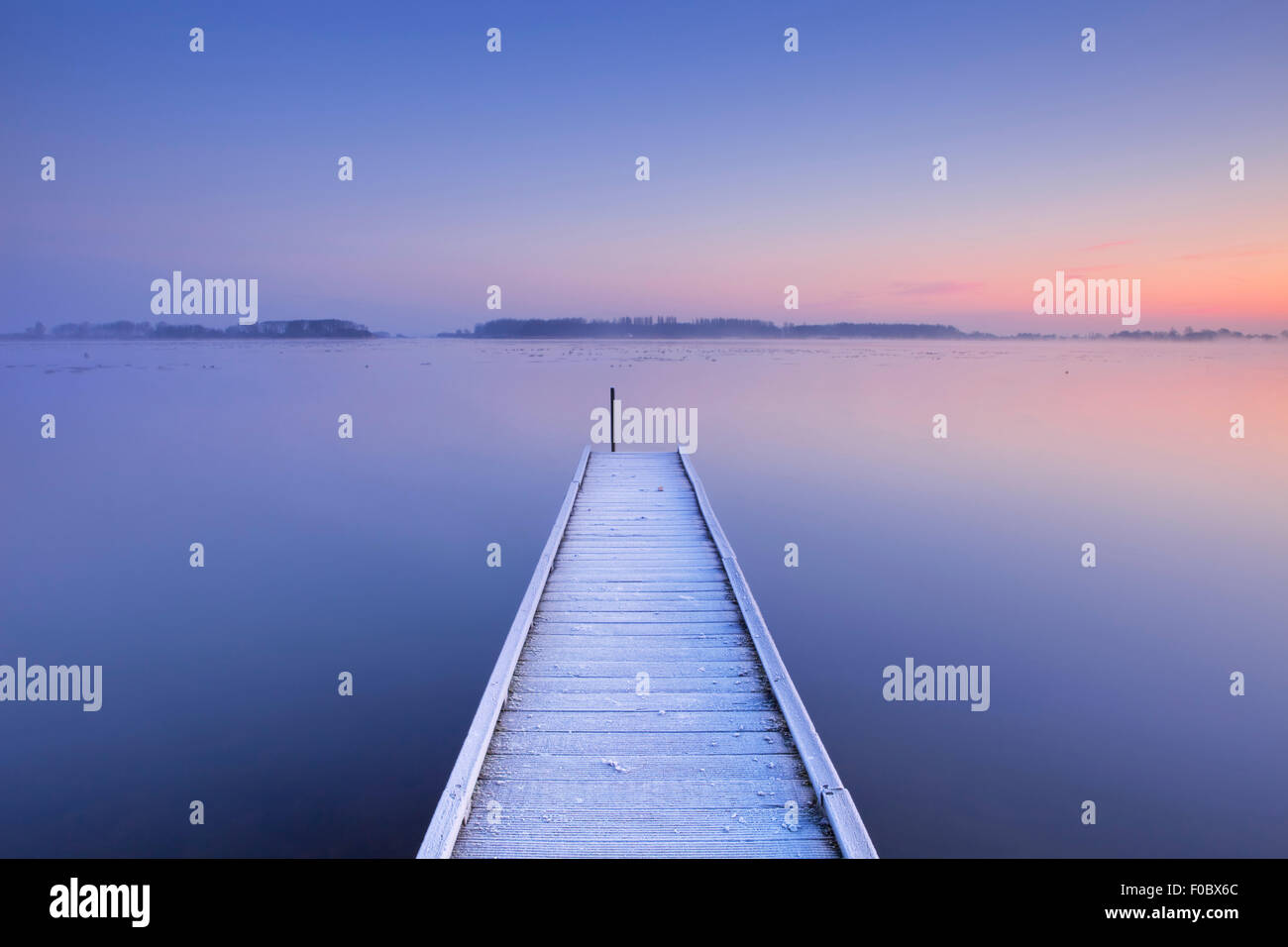 Einem ruhigen See in den Niederlanden mit einem Steg auf einer frühen Wintermorgens. Stockfoto