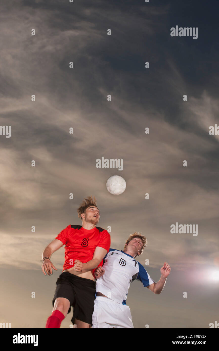 Männlichen Fußballer Richtung Ball gegen Himmel Stockfoto